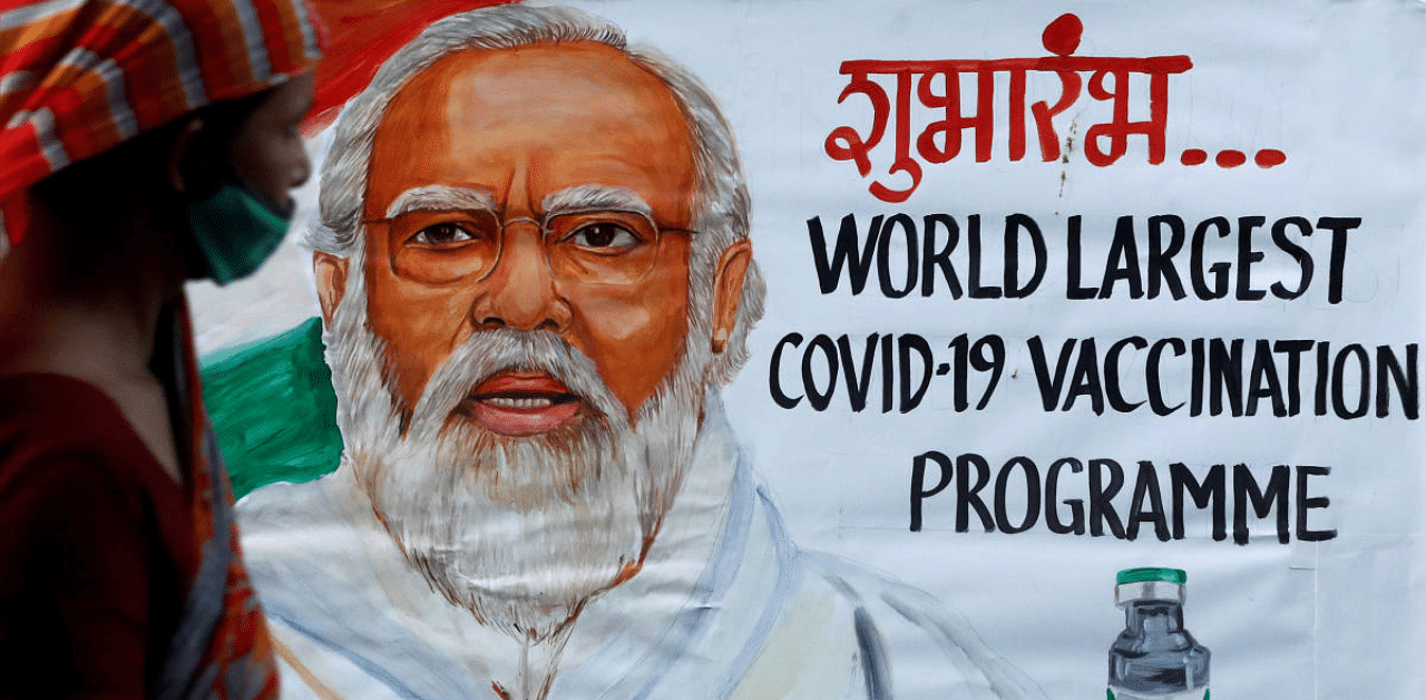 A woman walks past a painting of Indian Prime Minister Narendra Modi a day before the inauguration of the Covid-19 vaccination drive on a street in Mumbai. Credit: Reuters photo. 