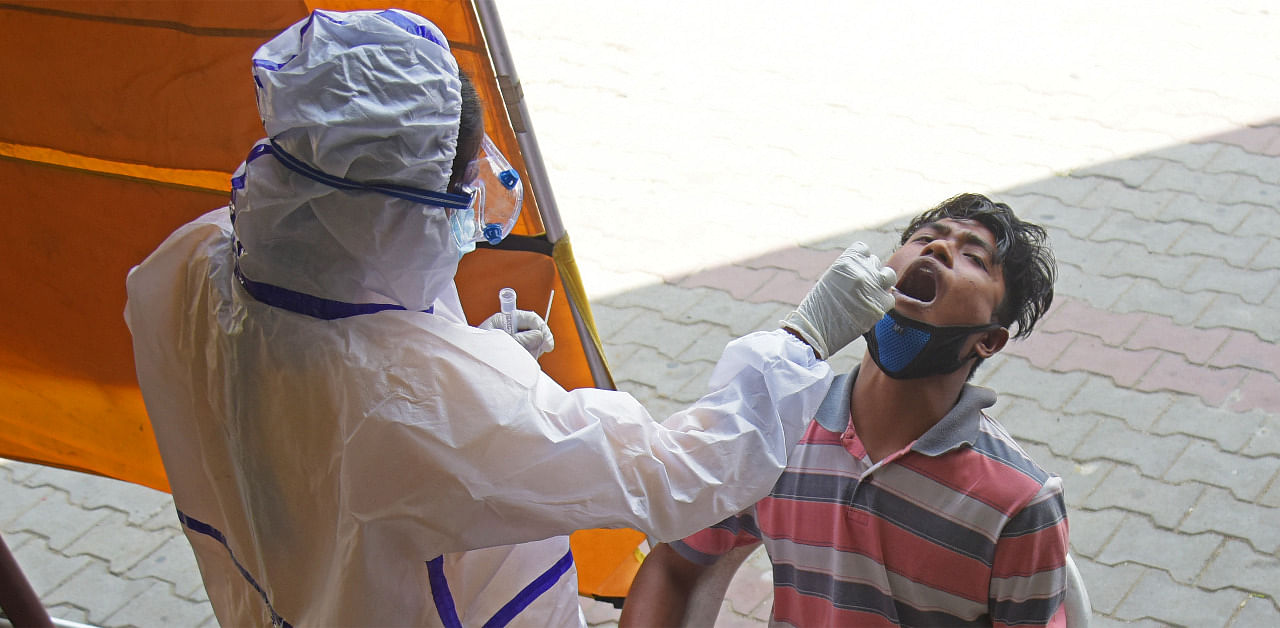 A health worker takes a swab of a passenger for a Covid-19 test in Bengaluru. Credit: DH Photo/Pushkar V