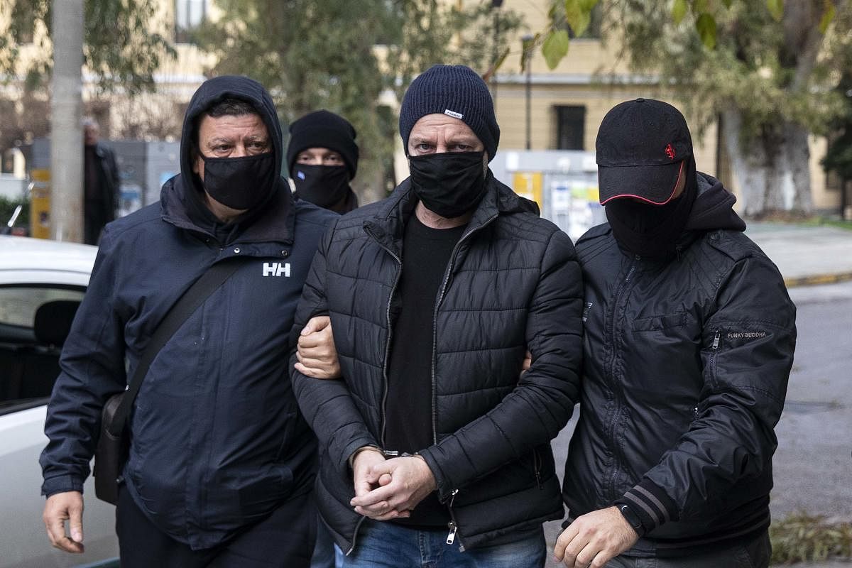 Plain-clothed policemen escort handcuffed well-known actor and director Dimitris Lignadis (C) to a magistrate's office in Athens. Credit: AP photo. 