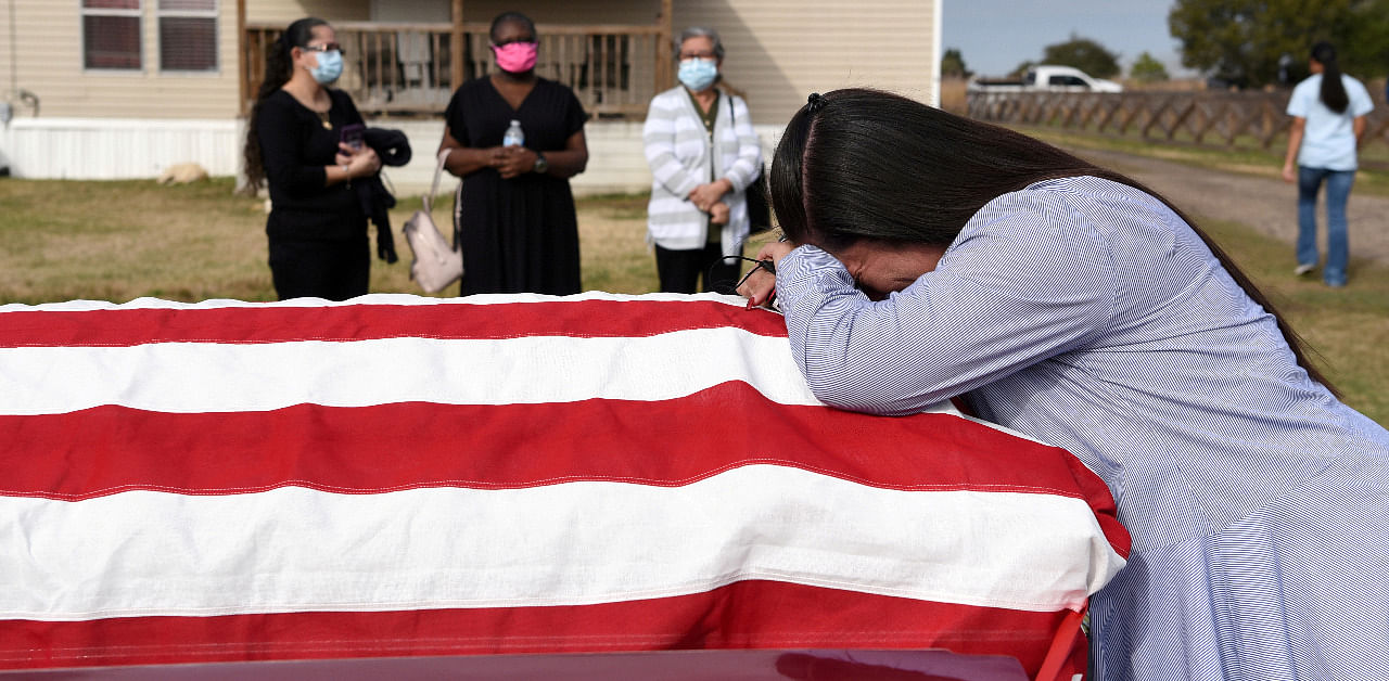 A woman holds the casket of her husband, who died of Covid-19. Credit: Reuters Photo
