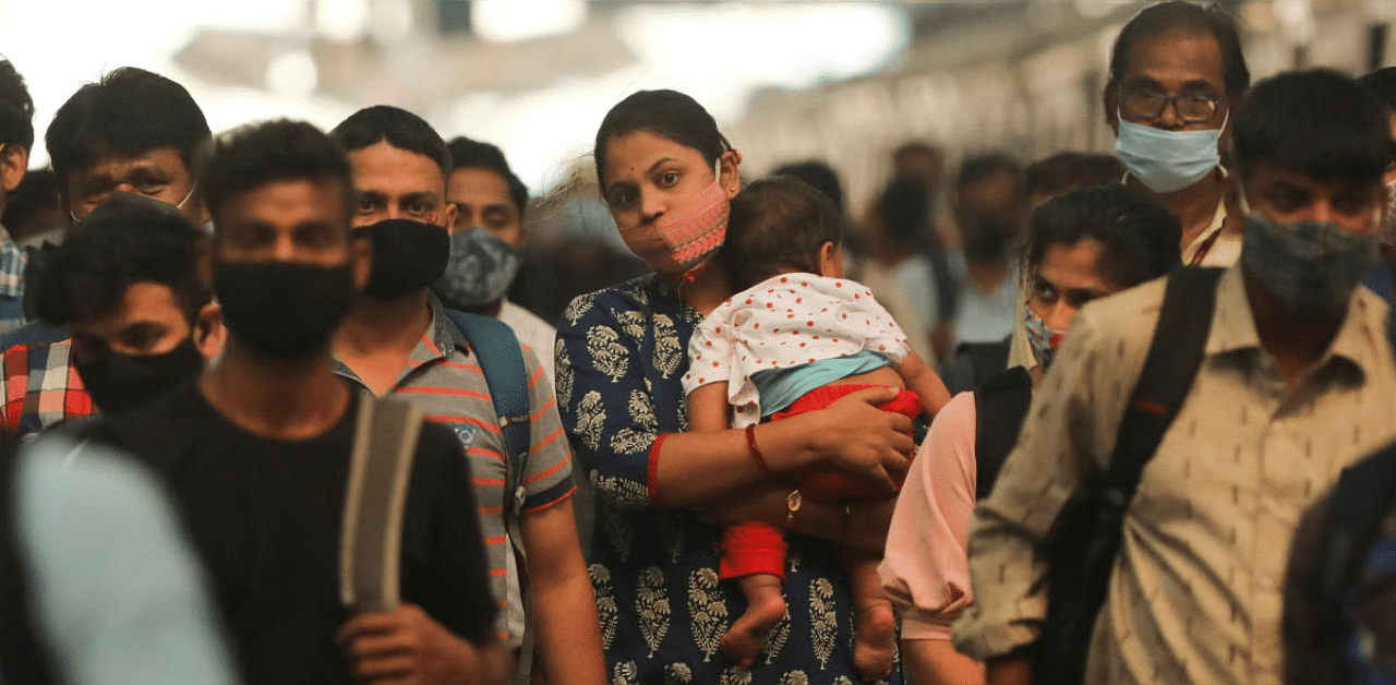 A woman carrying a child walks inside a railway station amidst the spread of the coronavirus disease in Mumbai, India. Credit: Reuters photo. 