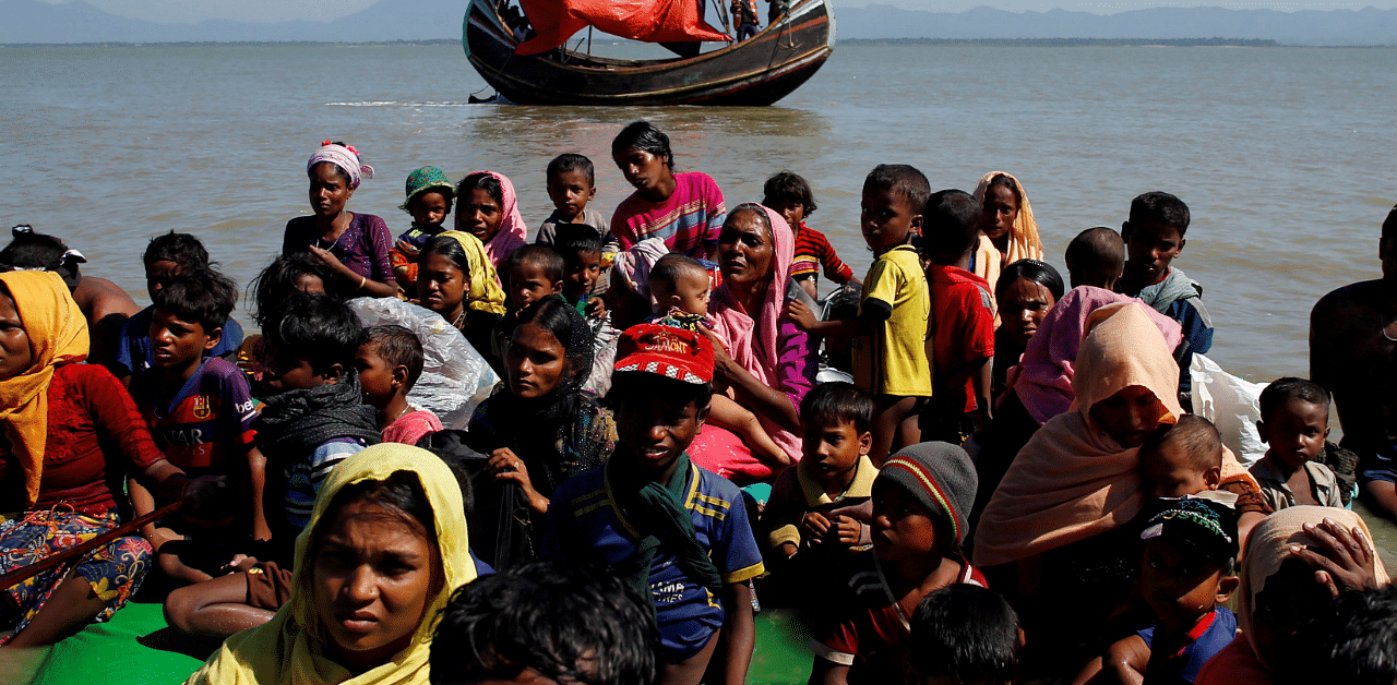 Rohingya refugees sit on a makeshift boat as they get interrogated by the Border Guard Bangladesh. Credit: Reuters Photo