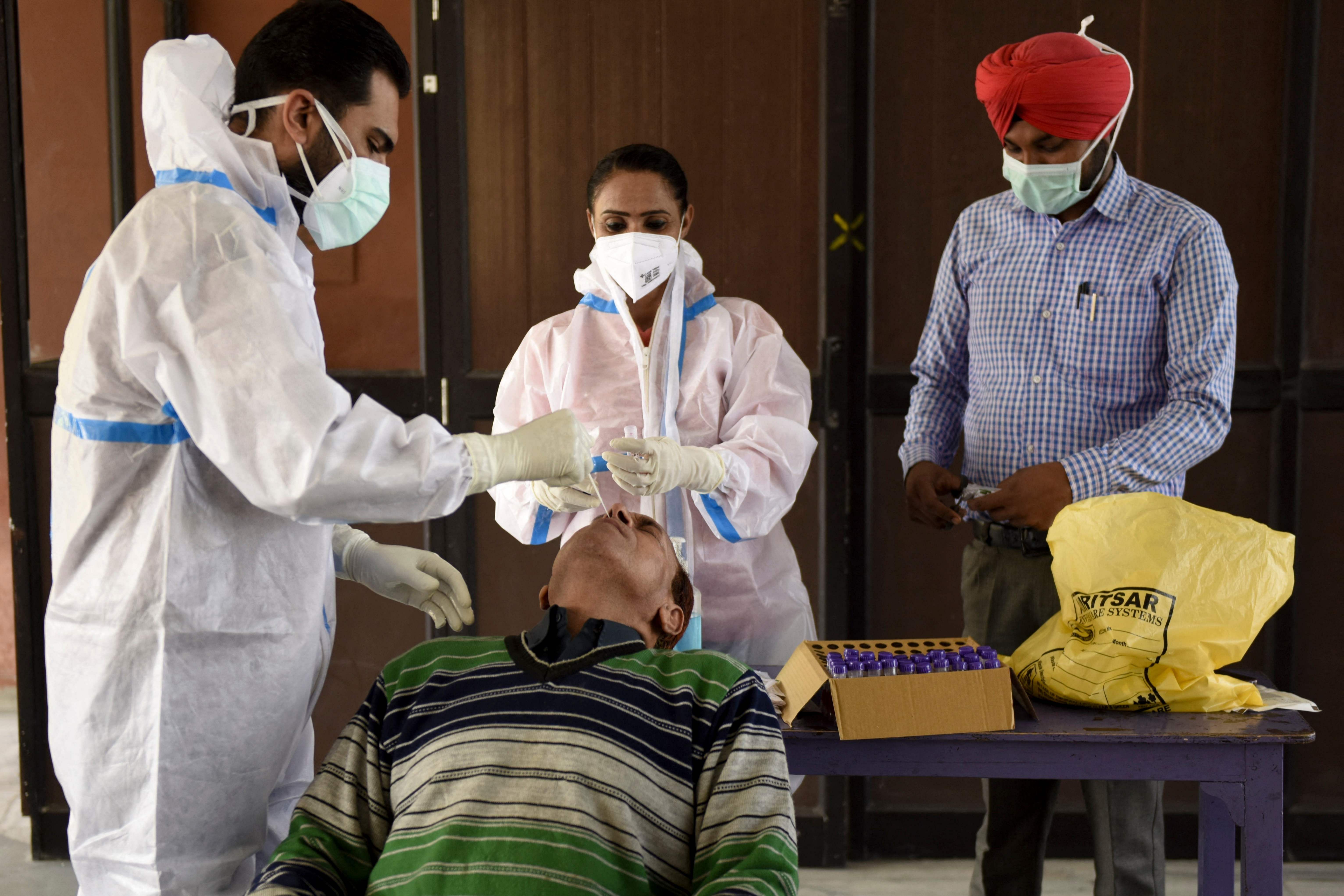 A health worker (L) collects a nasal swab sample from a teacher to test for the Covid-19 coronavirus at a school in Amritsar on February 26, 2021. Representative image/Credit: AFP Photo