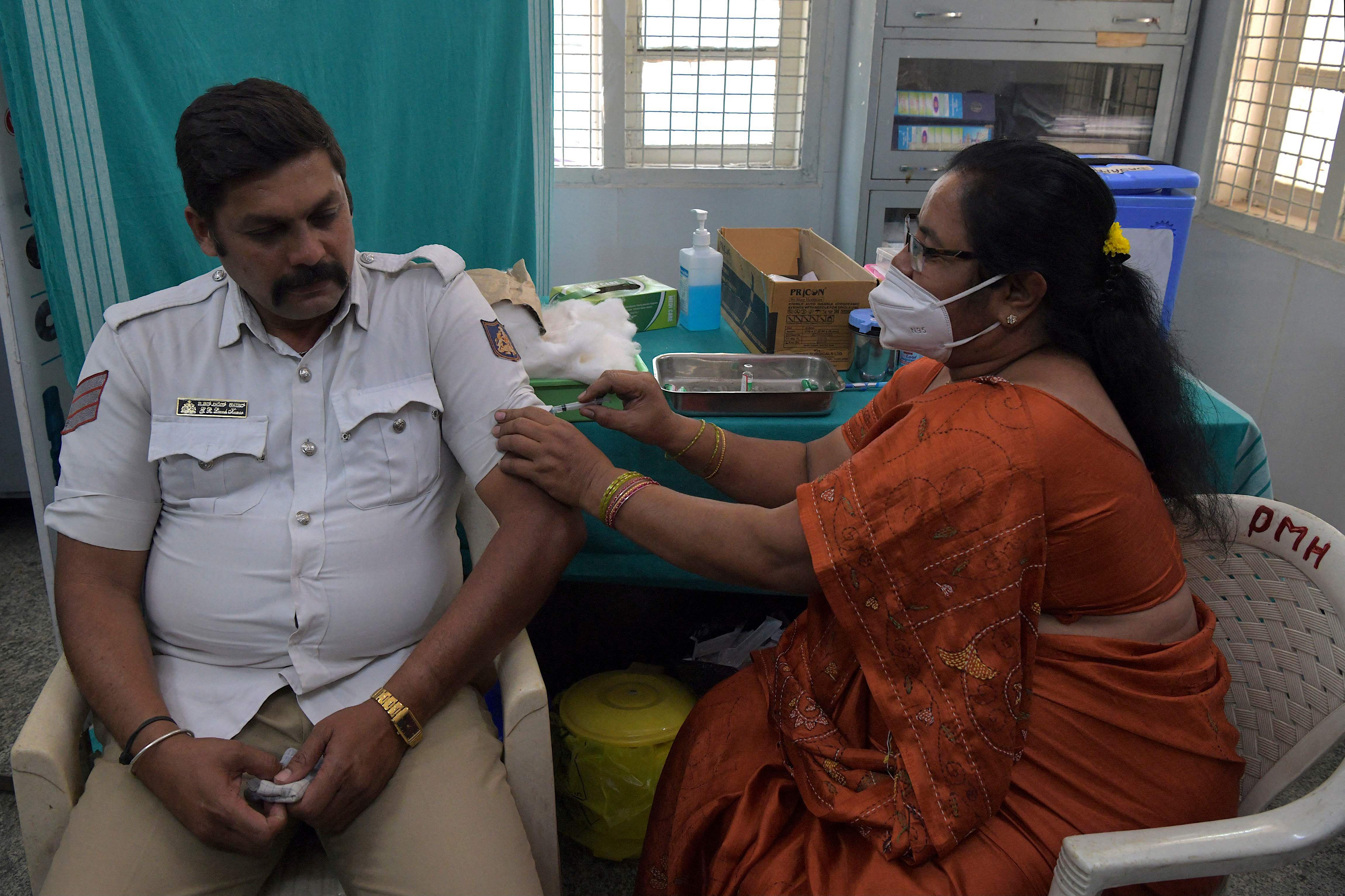 A medical worker inoculates a traffic policeman with a Covid-19 coronavirus vaccine at a hospital in Bangalore on February 26, 2021. Credit: AFP Photo