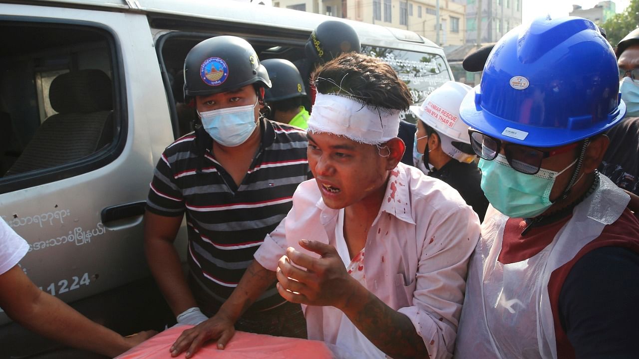 An injured protester is escorted as police tried to disperse a demonstration against the military coup in Mandalay, Myanmar. Credit: AP/PTI Photo