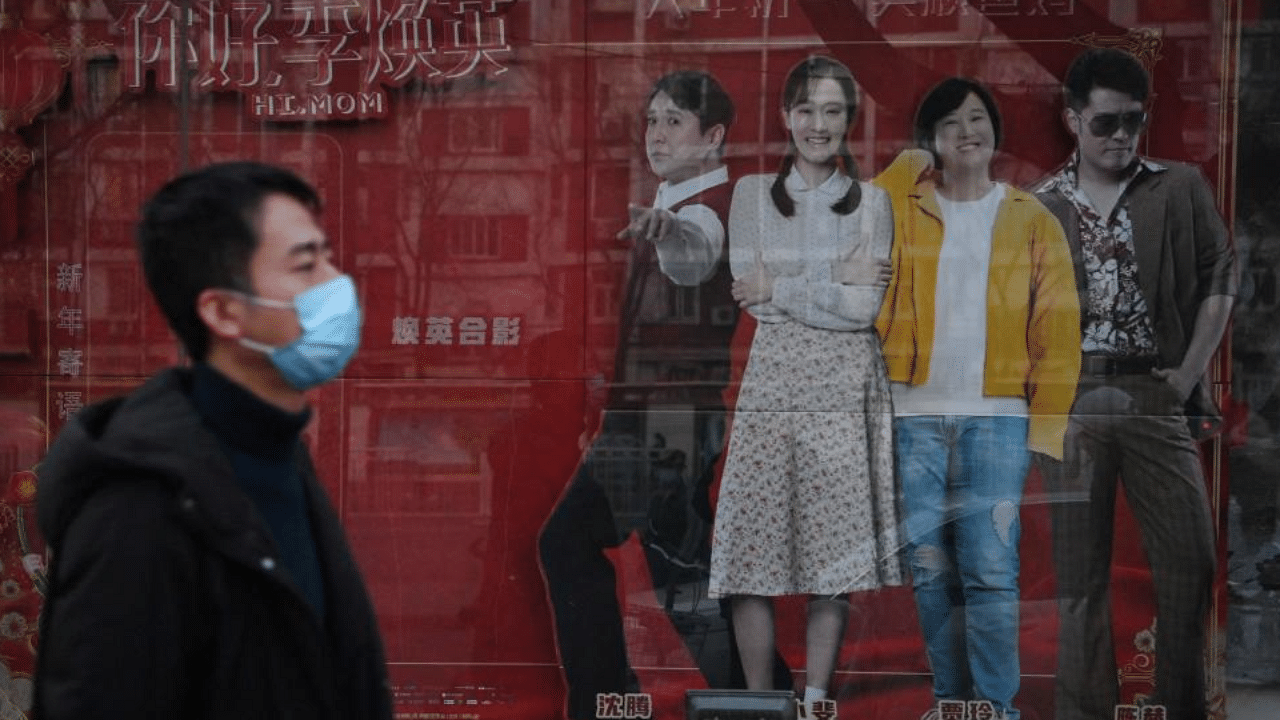 This photo taken on February 22, 2021 shows a man walking past a display for the movie "Hi, Mom" outside a cinema in Beijing. Credit: AFP Photo