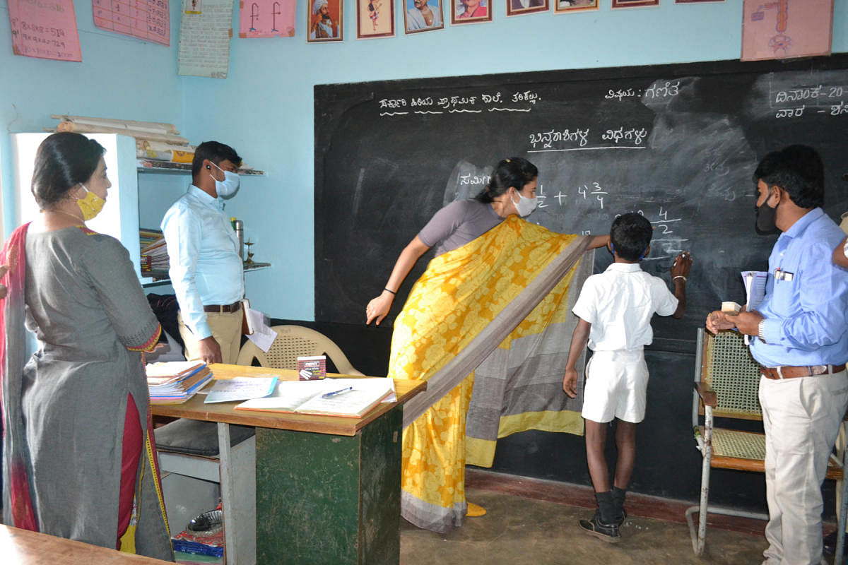 Mysuru Deputy Commissioner Rohini Sindhuri teaches mathematics to students during her visit to Tarikallu village in Hunsur taluk, Mysuru district, on Saturday. DH PHOTO