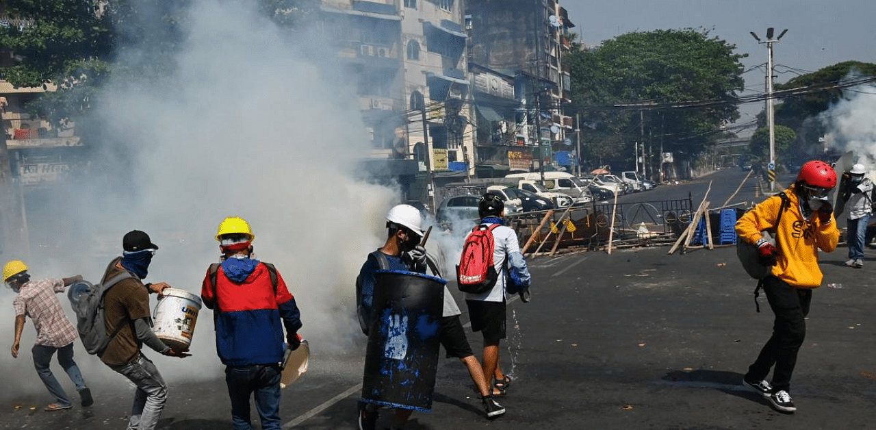 Protesters run to contain tear gas fired by security forces in an attempt to disperse them during a demonstration against the military coup in Yangon. Credit: AFP Photo