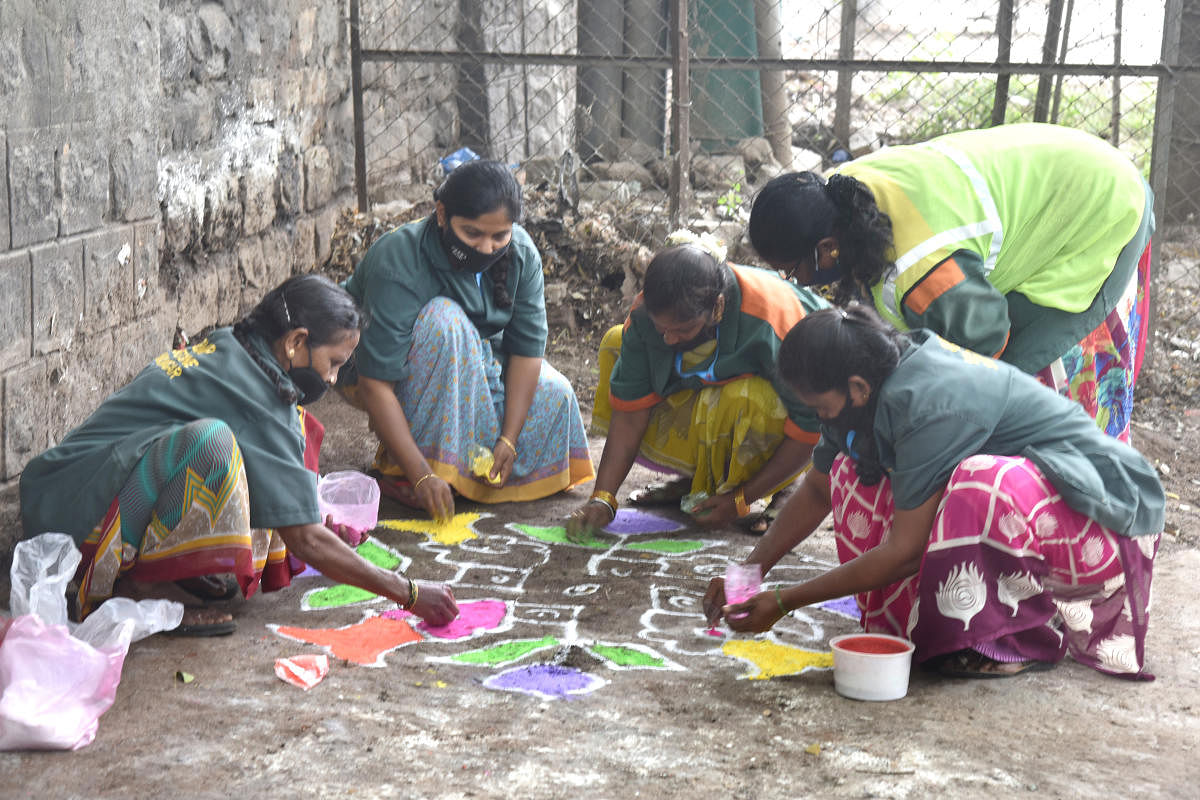 Municipal workers draw rangoli after cleaning up a garbage black spot on Thimmaiah Road, Shivajinagar, in Bengaluru. Credit: DH File Photo/S K DINESH