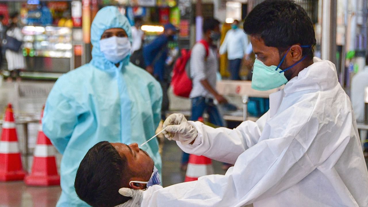 A health worker takes a nasal swab sample of a passenger for coronavirus tests at the CSMT railway station. Credit: PTI File Photo