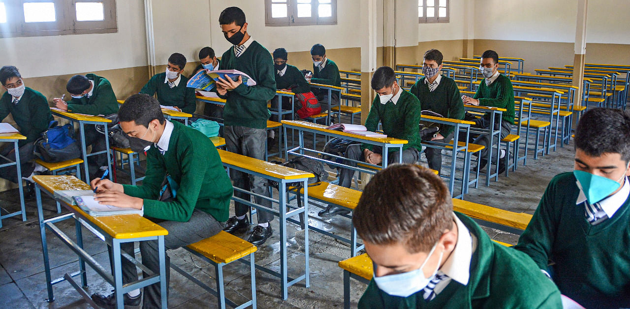 Students wearing masks attend a class after schools resumed for the students of classes 9th to 12th, with certain COVID-19 safety guidelines, in Srinagar. Credit: PTI Photo