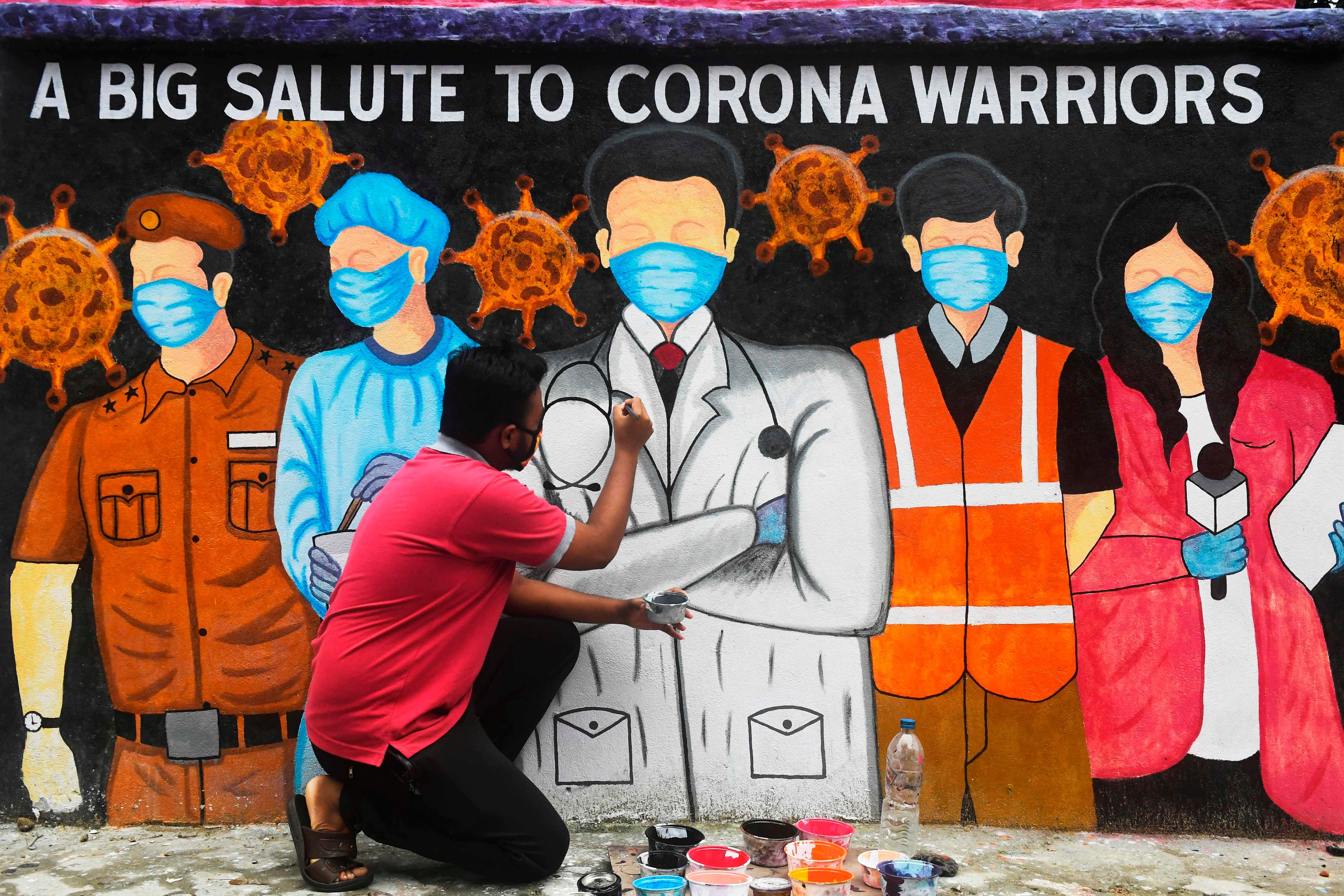 An artist gives finishing touches to a mural depicting frontline workers in Kolkata. Representative image/Credit: AFP Photo