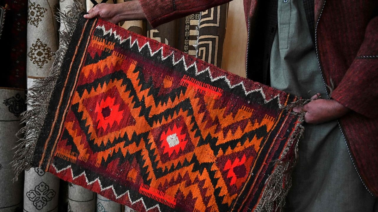 In this picture taken on January 7, 2021, a vendor displays a rug at his shop in Bamiyan. Credit: AFP Photo