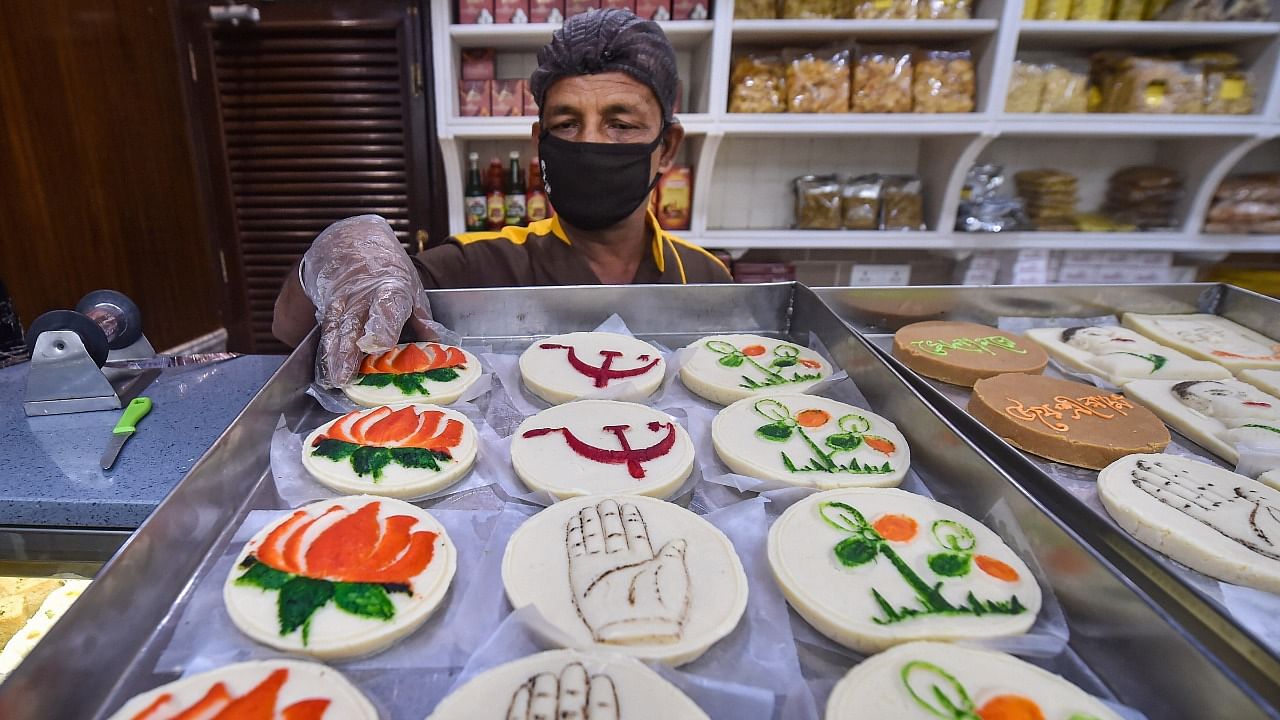 A vendor displays sweets with different political party symbols at his sweet shop, ahead of the State Assembly elections, in Kolkata. Credit: PTI Photo