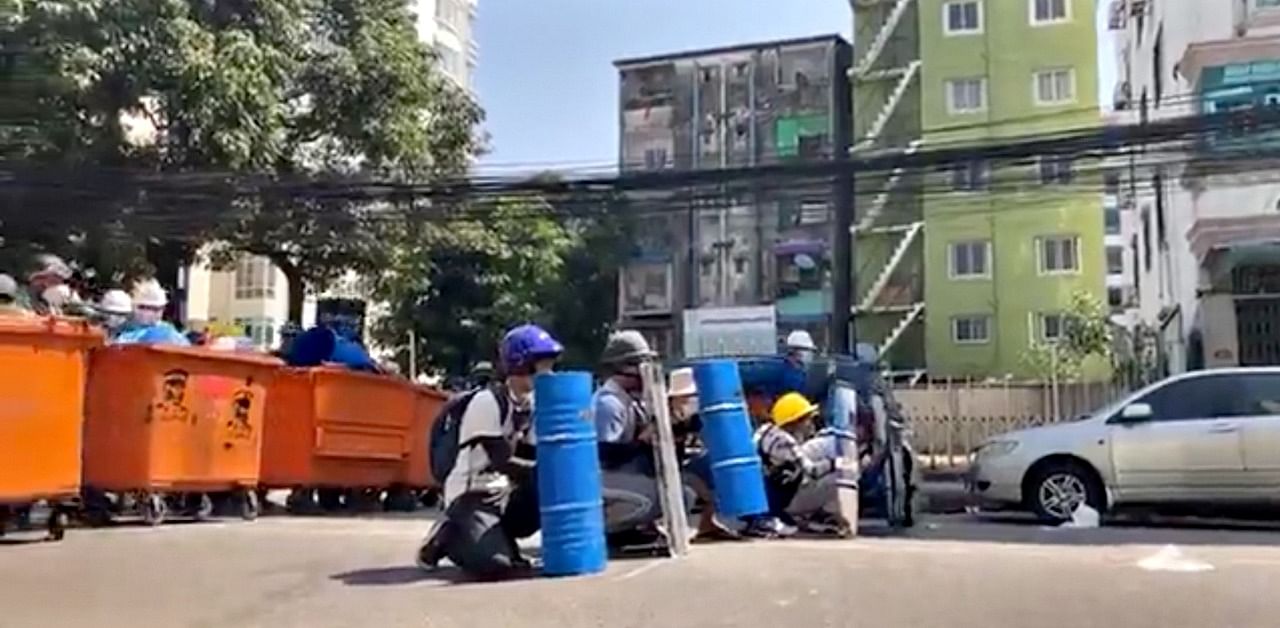 Protesters hide behind barricades during an anti-coup protest in Yangon, Myanmar Credit: Myanmar Now via Reuters