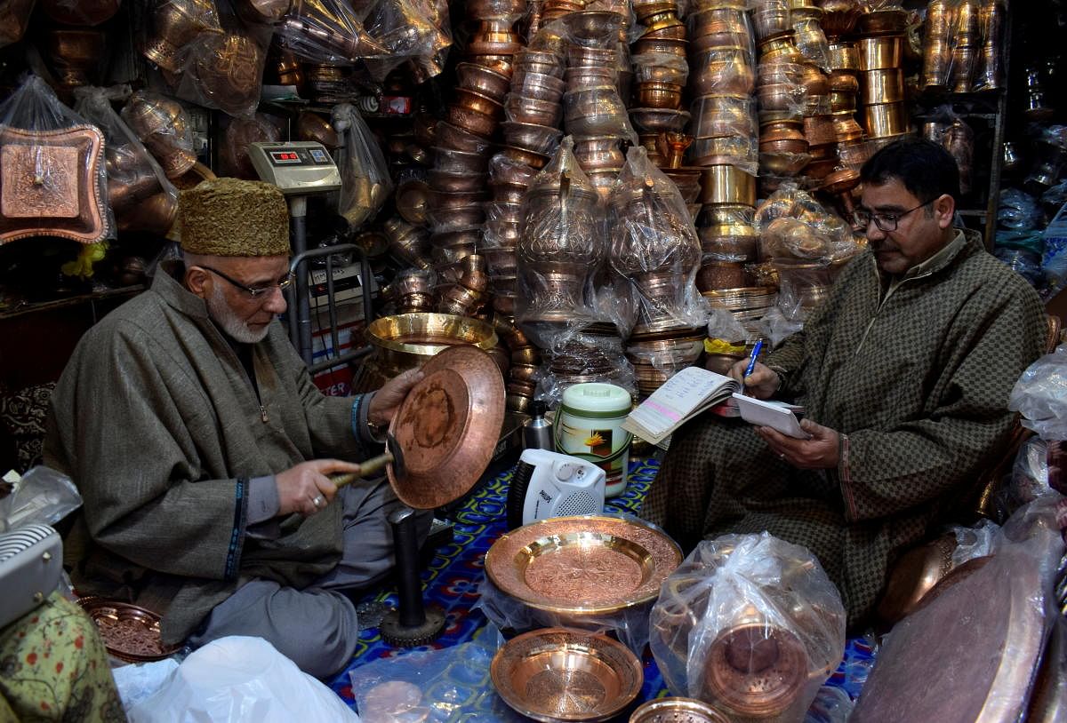 A Kashmiri shopkeeper selling copperware fixes a copper plate for a customer at his shop in downtown Srinagar March 1, 2021. Picture taken March 1, 2021. Credit: REUTERS