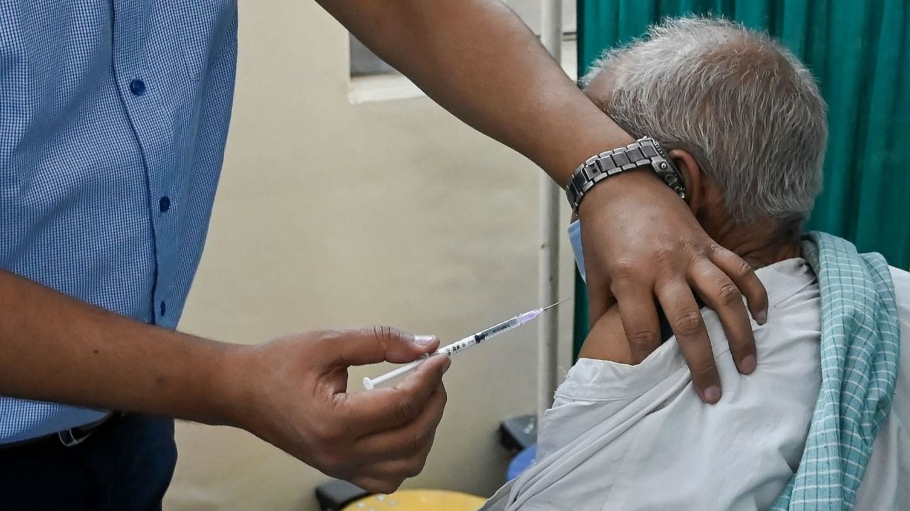 A medical worker inoculates an elderly man with a Covid-19 coronavirus vaccine at vaccination centre in New Delhi on March 5, 2021. Credit: AFP Photo