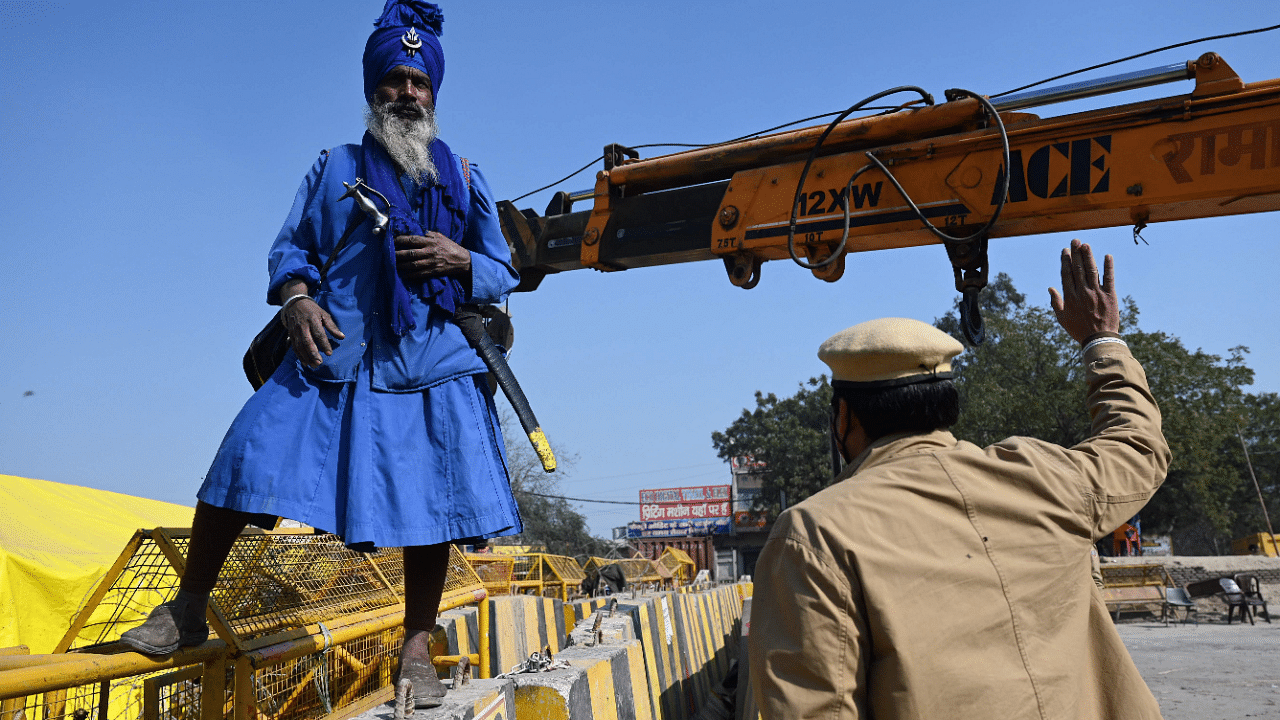 A Nihang, or a Sikh Warrior, watches as police set up road blocks at the Delhi-Haryana state border in Singhu. Credit: AFP Photo