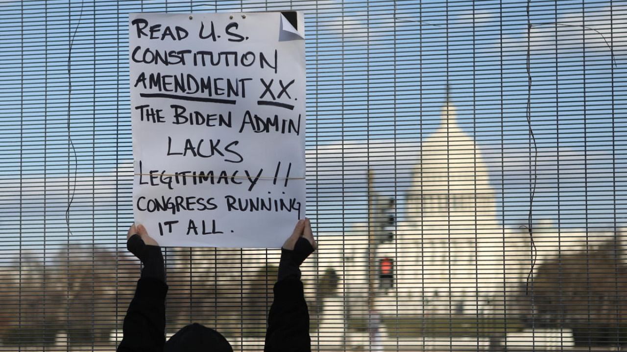 A protester holds up a sign outside the security perimeter fence surrounding the US Capitol in Washington. Credit: Reuters.