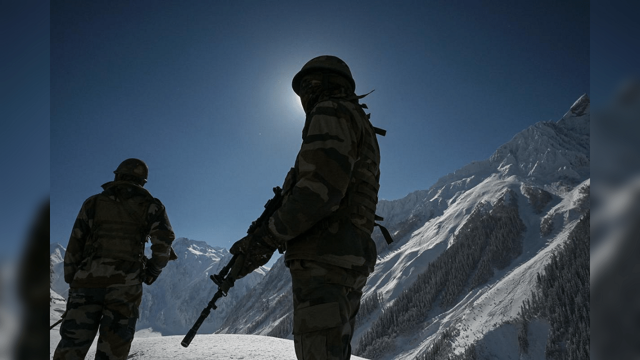 Indian army soldiers stand on a snow-covered road near Zojila mountain pass that connects Srinagar to the union territory of Ladakh, bordering China on February 28, 2021. AFP Photo