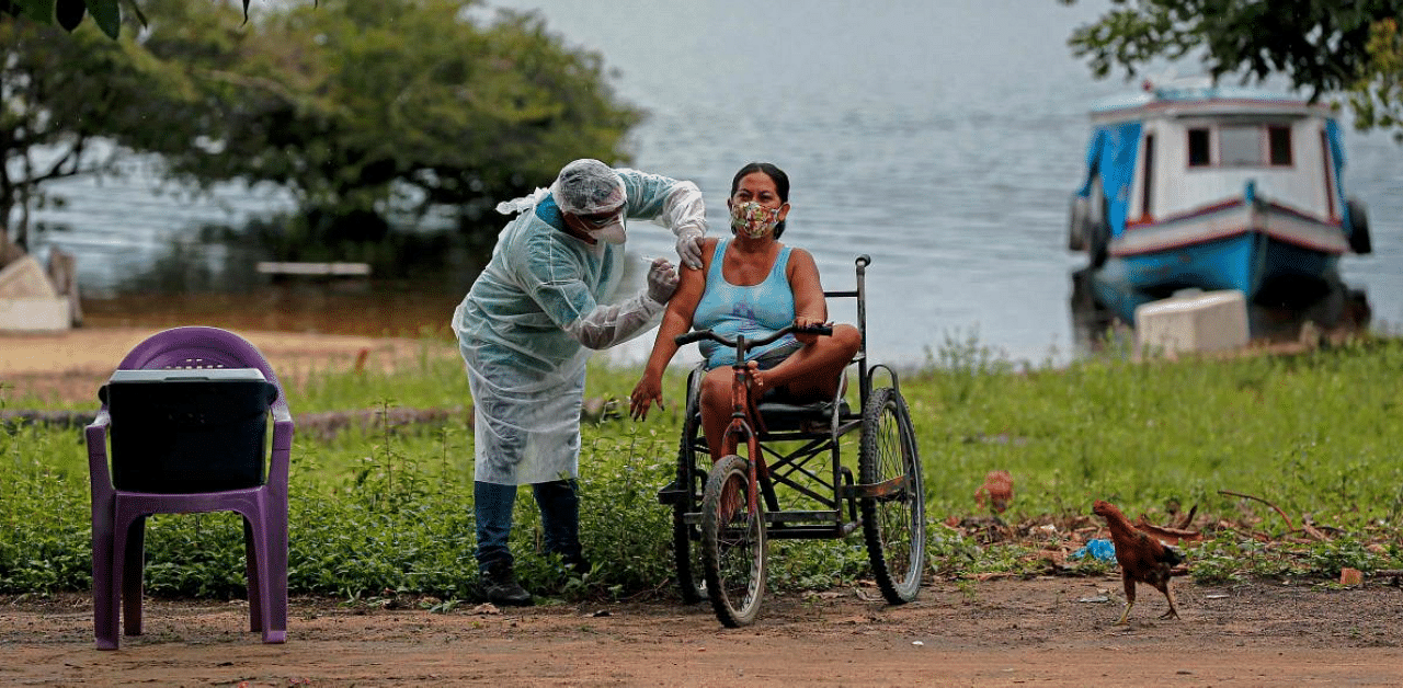 A health worker from the Ministry of Health Department for Indigenous Health adminsters a second doses of a COVID-19 vaccine to a woman in the village Esperanca do Rio Arapiun. Credit: AFP Photo