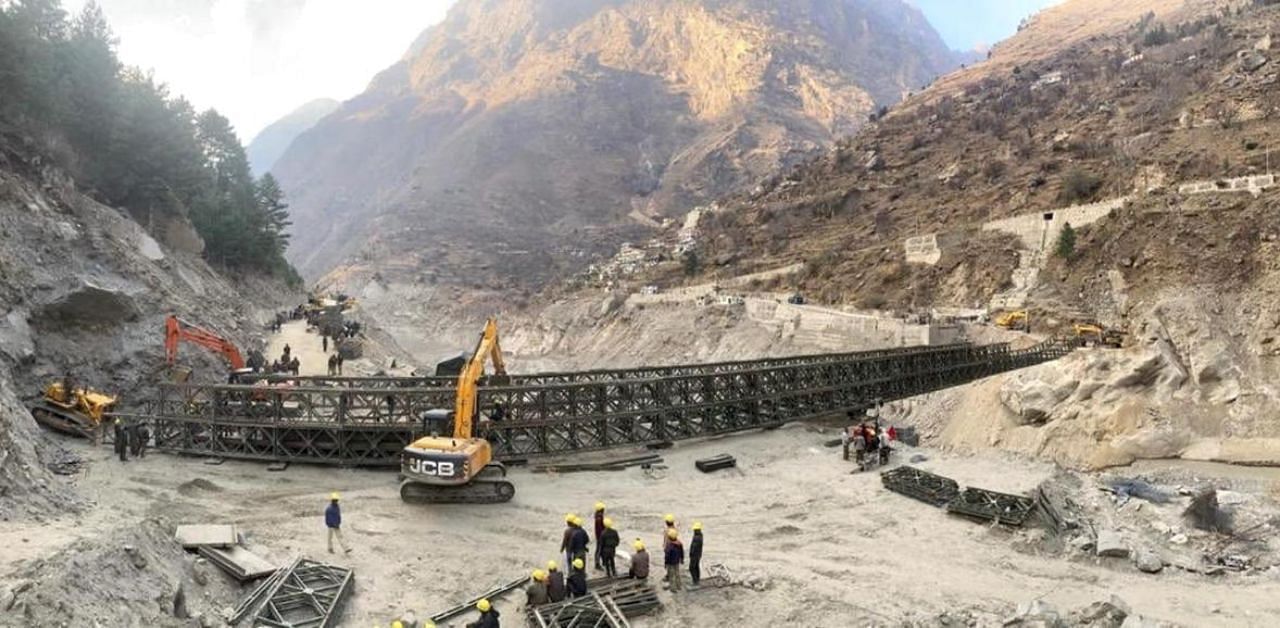  Border Roads Organisation (BRO) workers engaged in building a valley bridge over the Rishi Ganga River at Raini village of the disaster-hit Chamoli district. Credit: PTI photo. 