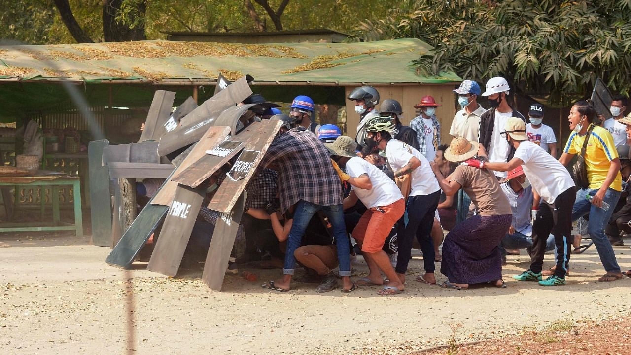 Protesters shelter behind shields as they face security forces during a demonstration against the military coup next to Shwezigon Pagoda in Nyaung-U near the UNESCO world heritage site Bagan. Credit: AFP Photo