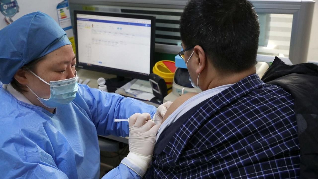 A medical worker (L) administers a does of Covid-19 coronavirus vaccine to a man at a community health center in Nantong, in eastern China's Jiangsu province. Credit: AFP.