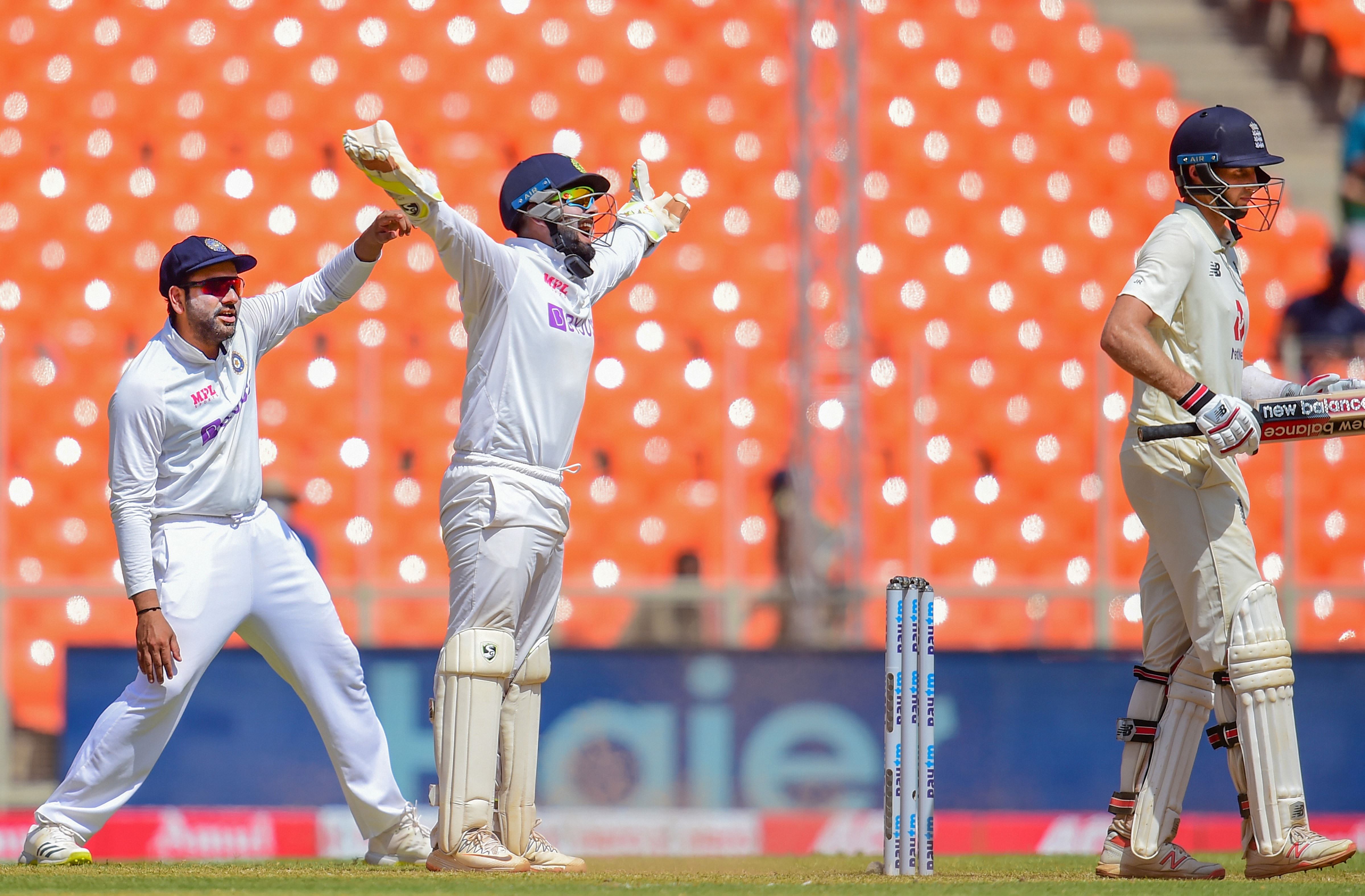 Indian wicket-keeper R Pant with teammate Rohil Sharma celebrates the wicket of England batsman Joe Root during the third day of the 4th and last cricket test match between India and England, at the Narendra Modi Stadium in Ahmedabad, Saturday, March 6, 2021. Credit: PTI Photo