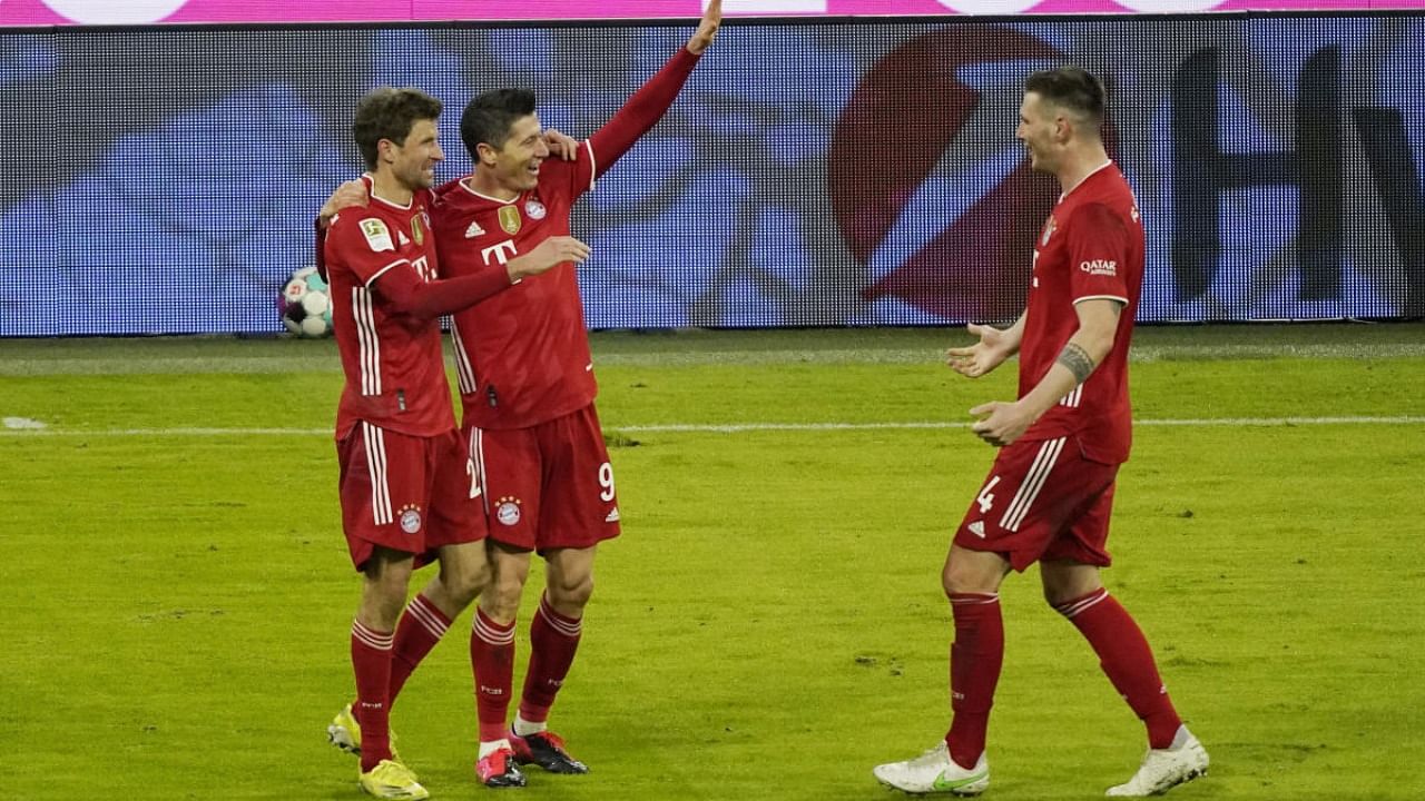 Bayern Munich's Robert Lewandowski celebrates scoring their fourth goal with Thomas Muller and Niklas Sule. Credit: Reuters.