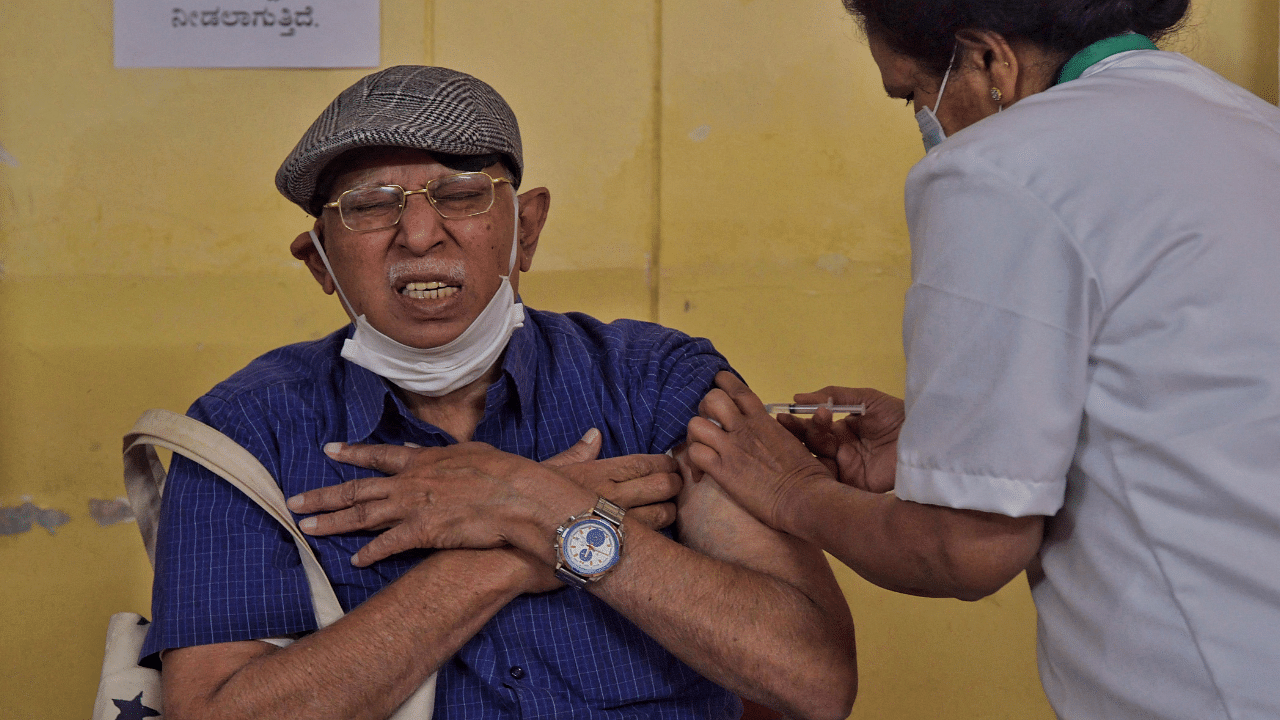 A health worker (L) inoculates a senior citizen with a Covid-19 coronavirus vaccine at a government hospital. Credit: AFP Photo