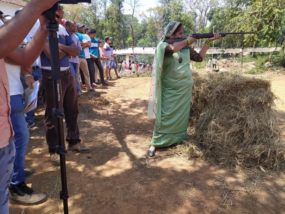 A woman takes aim in the coconut shooting competition. Credit: DH photo. 