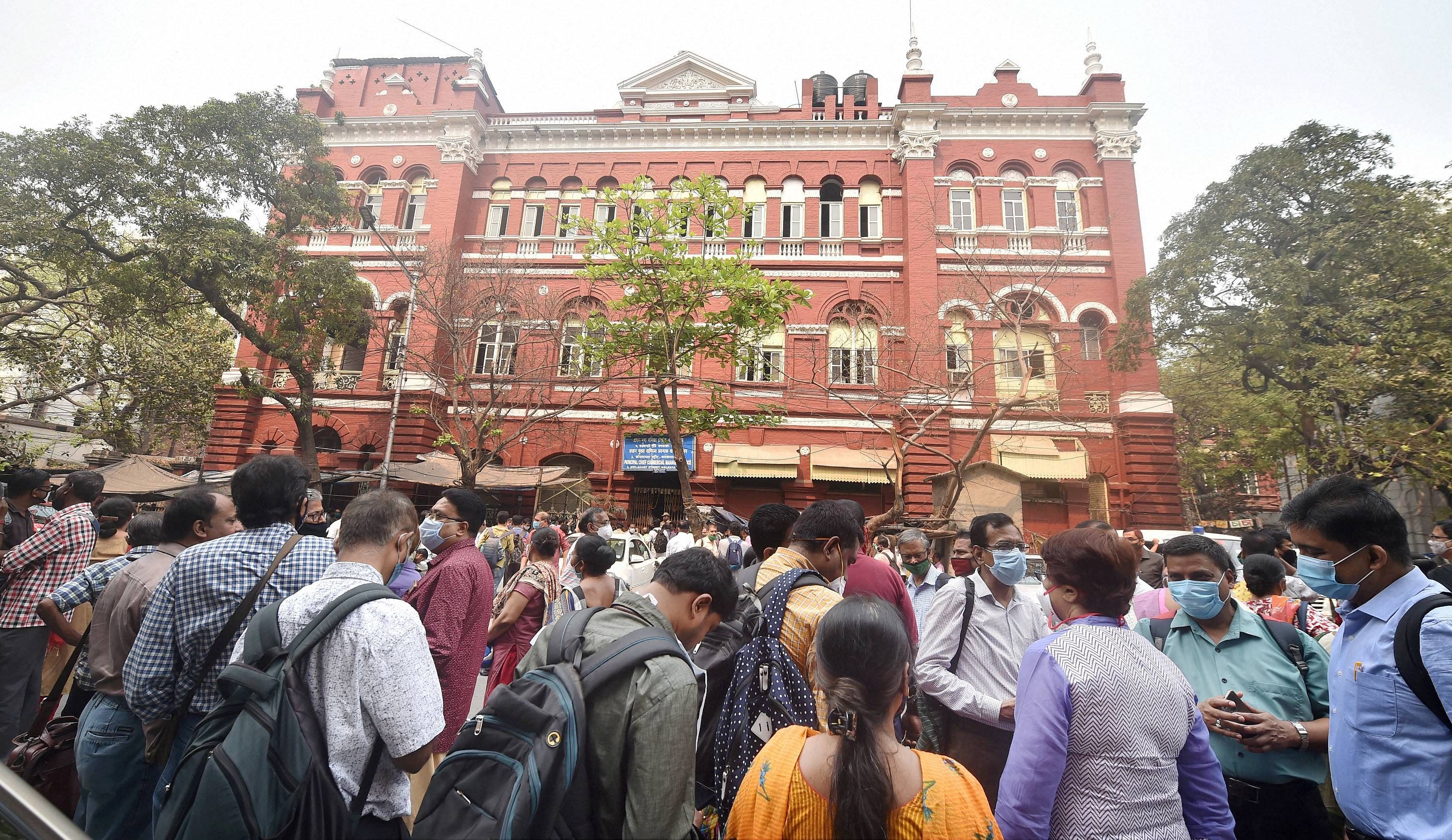 Railways employees stand on the road as they are not allowed to enter the New Koilaghat building (Eastern Railway HQ), a day after a fire, in Kolkata. Credit: PTI Photo