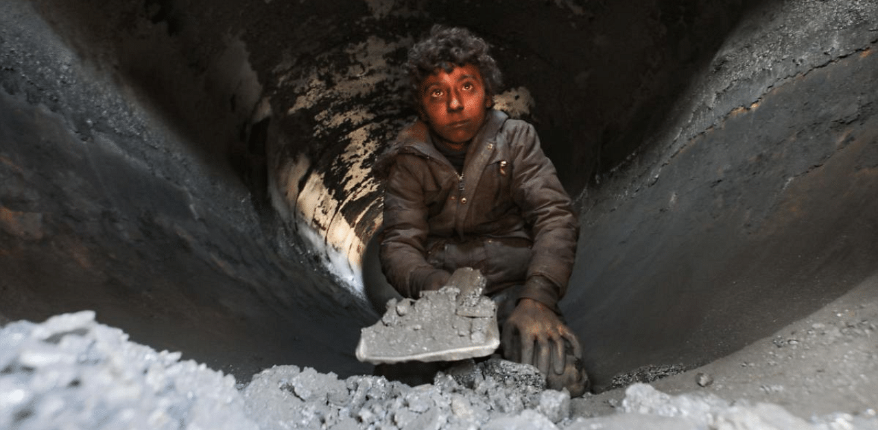 A displaced young Syrian boy works at a makeshift oil refinery near the village of Tarhin. Credit: AFP photo. 