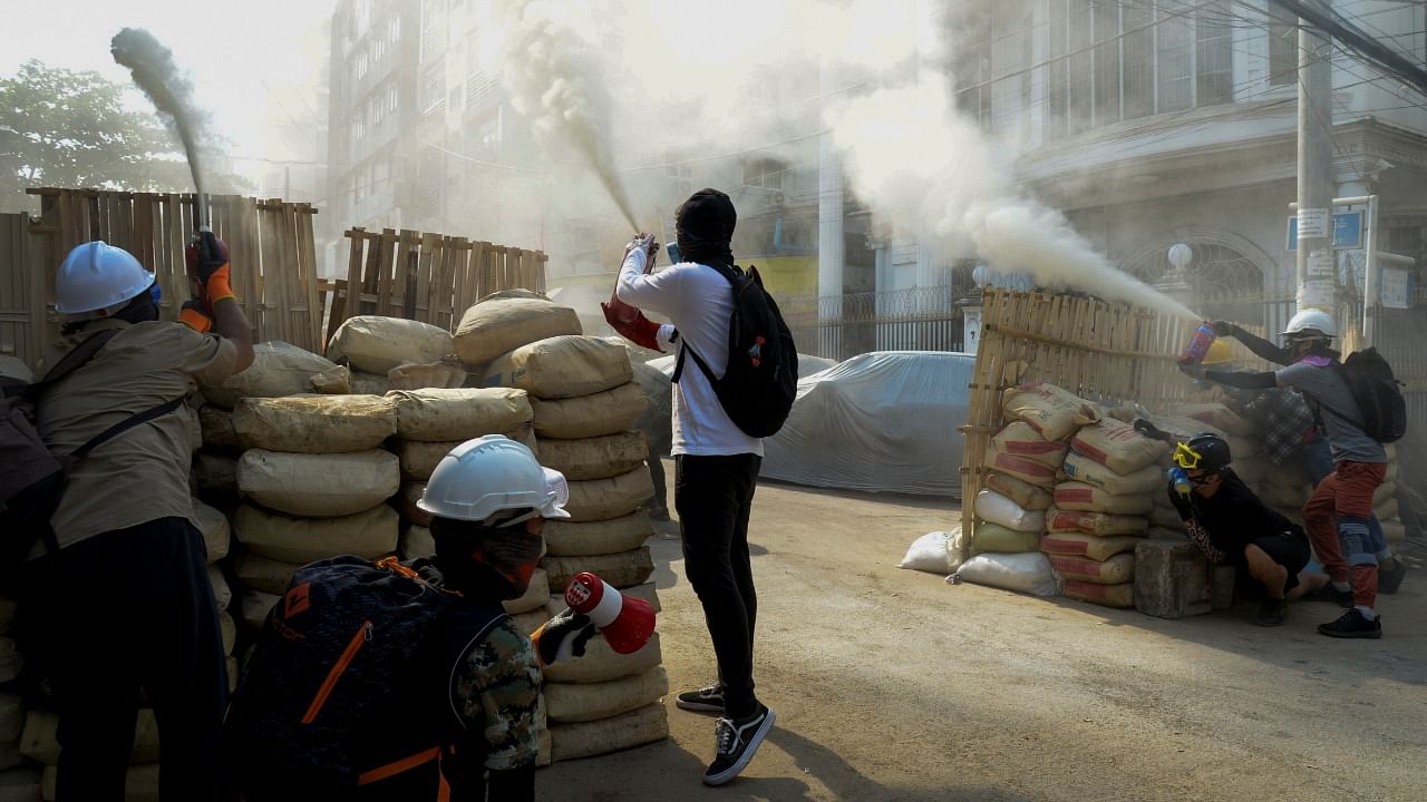 Anti-coup demonstrators sprays fire extinguishers over a barricade during a protests in Yangon, Myanmar. Credit: Reuters Photo