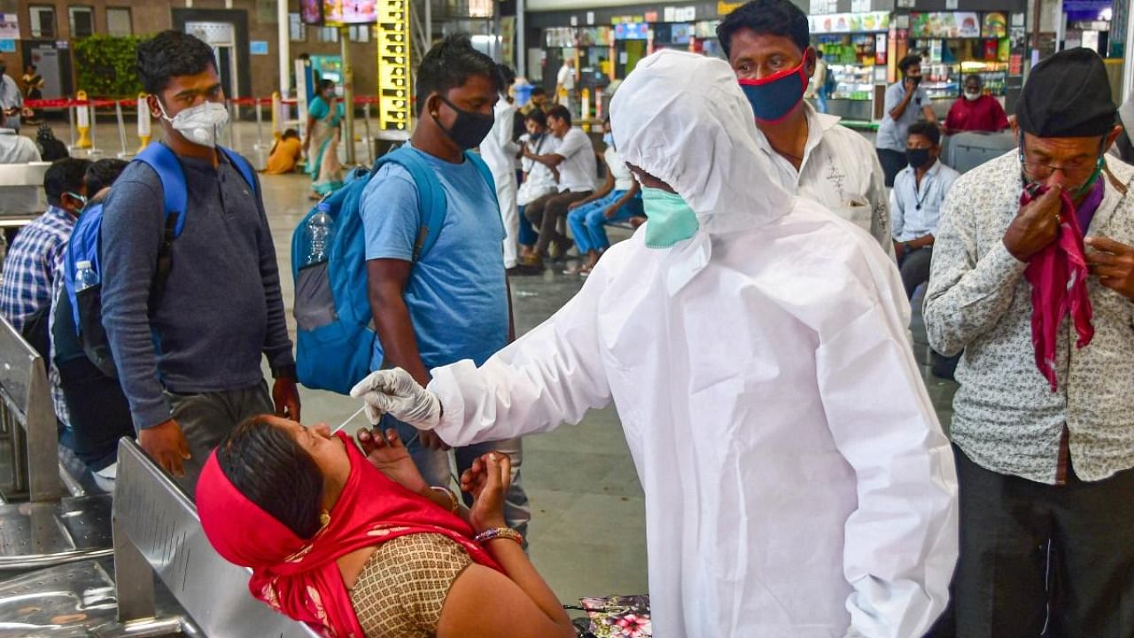A health worker conducts Covid-19 testing of a passenger at Chhatrapati Shivaji Maharaj Railway Terminus, amid surge in coronavirus cases in Mumbai. Credit: PTI.