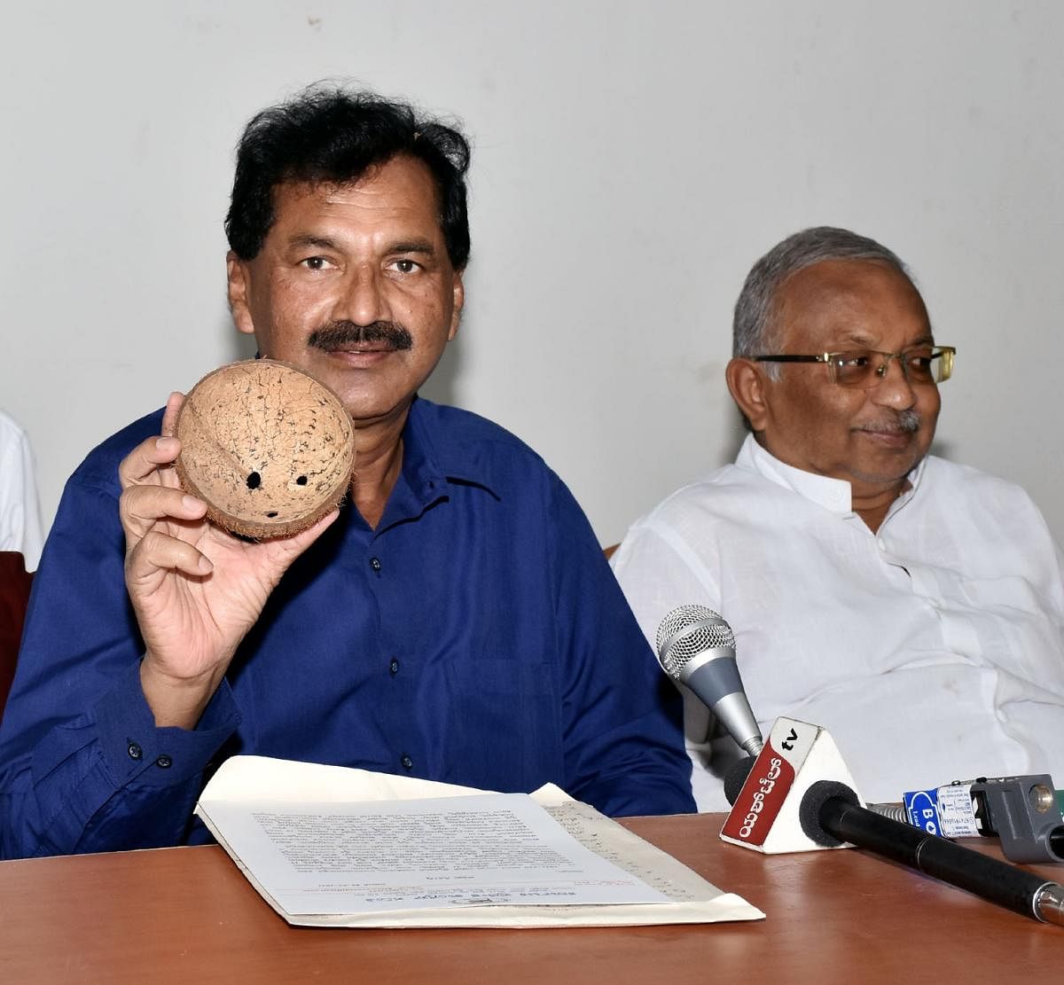 KPCC spokesperson M Lakshmana condemns the state budget by displaying a coconut shell, in Mysuru on Tuesday.  DH PHOTO
