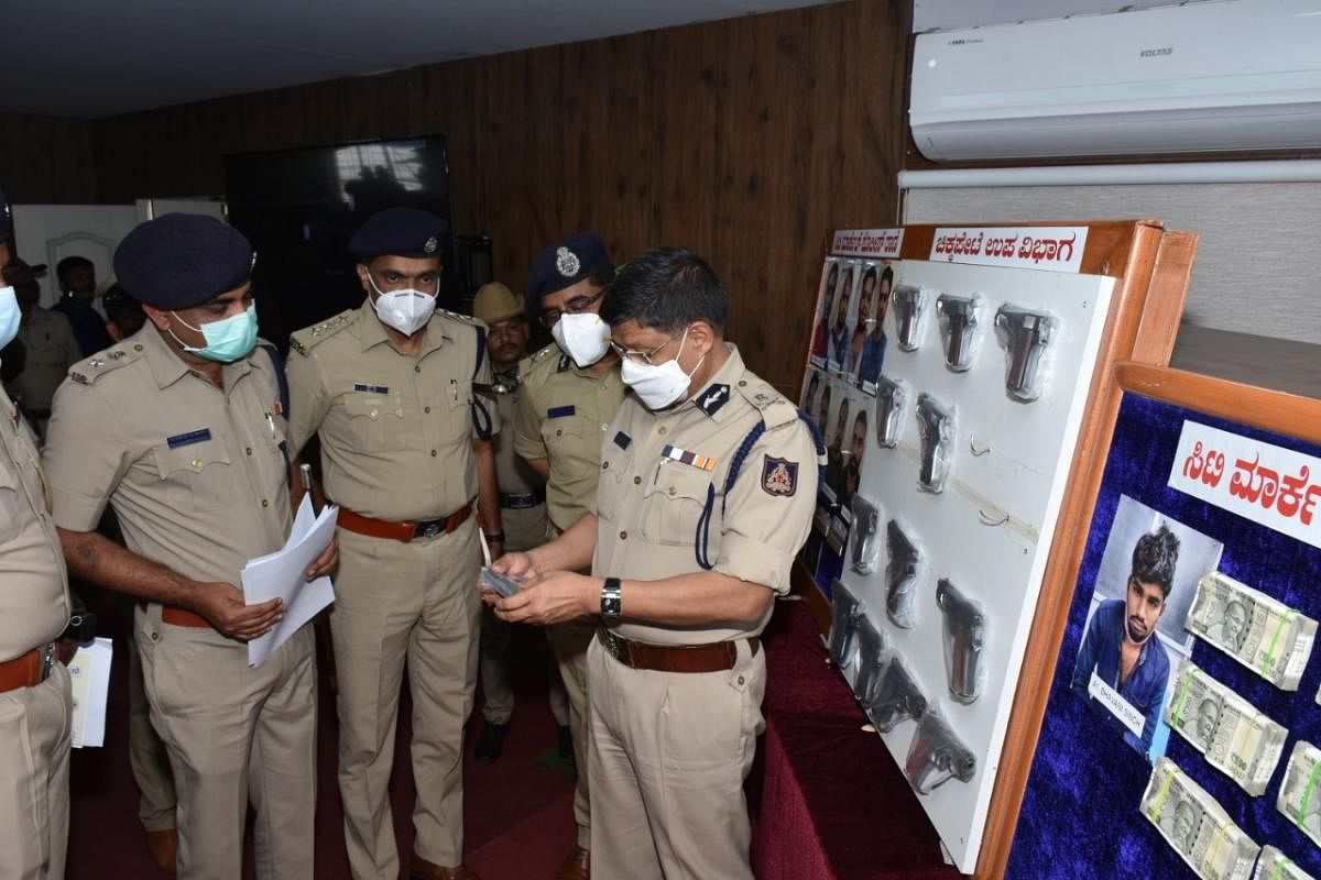 A Bengaluru police team examines a gun seized in an operation that took them to many states.