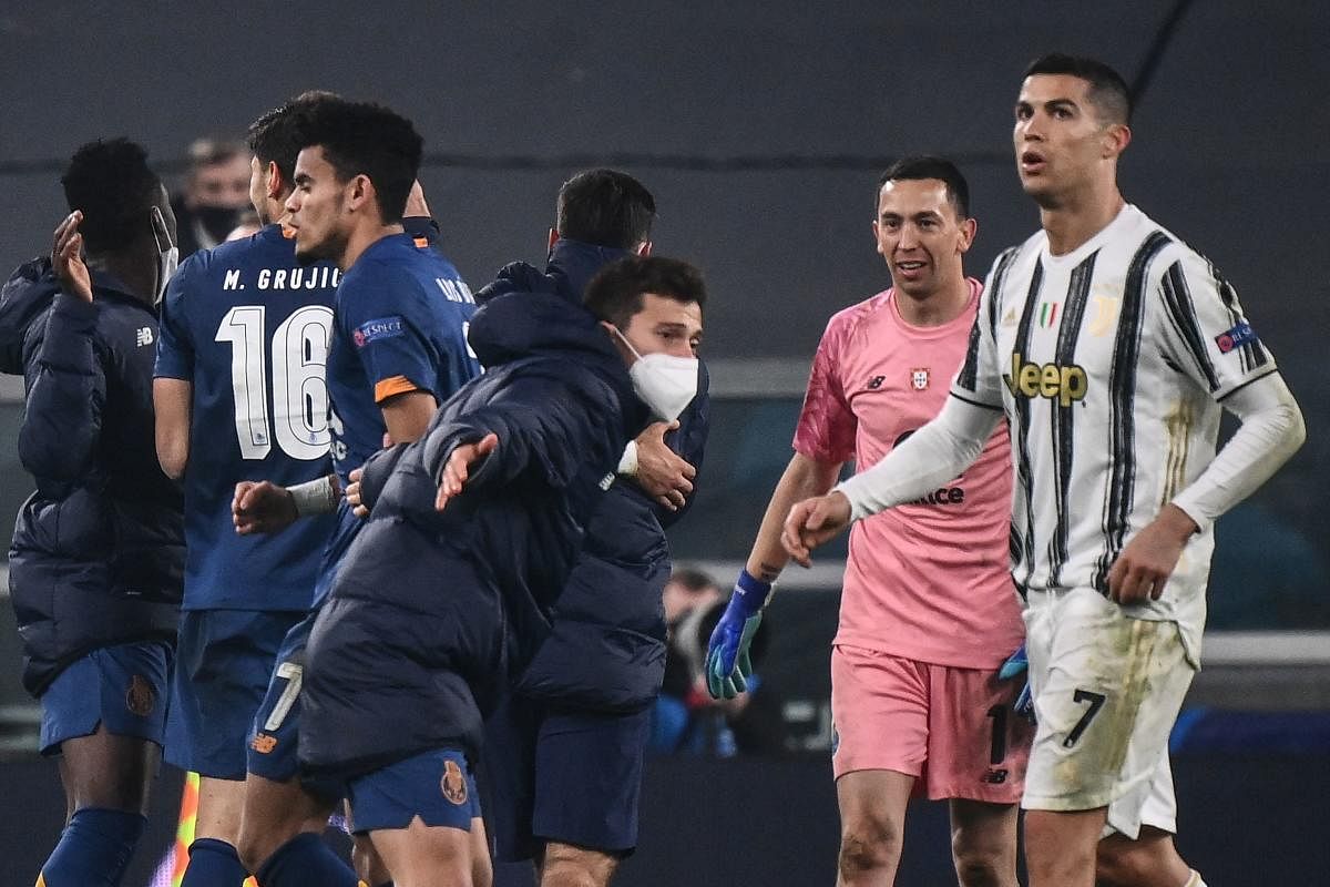 Cristiano Ronaldo (R) reacts as FC Porto's players celebrate at the end of the UEFA Champions League round of 16 second leg football match between Juventus Turin and FC Porto. Credit: AFP photo. 
