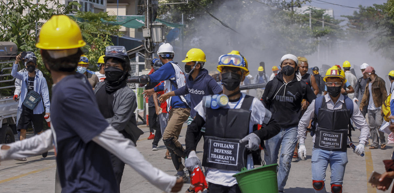 Anti-coup protesters retreat from the frontlines after discharging fire extinguishers towards a line of riot policemen in Yangon, Myanmar. Credit: AP photo. 