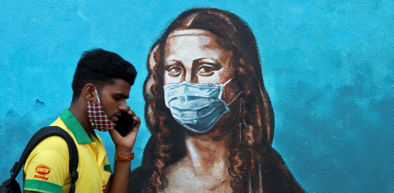 A man walks past a mural depicting the "Mona Lisa" wearing a face mask amidst the spread of Covid-19. Credit: Reuters Photo