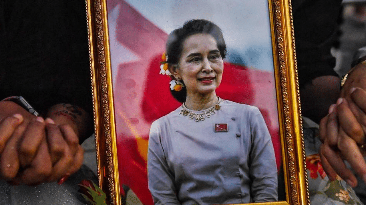 A picture of detained civilian leader Aung San Suu Kyi is seen as Myanmar migrants living in Thailand hold hands during a memorial in Bangkok on March 4, 2021 to honour those who died during demonstrations against the military coup in their homeland. Credit: AFP Photo