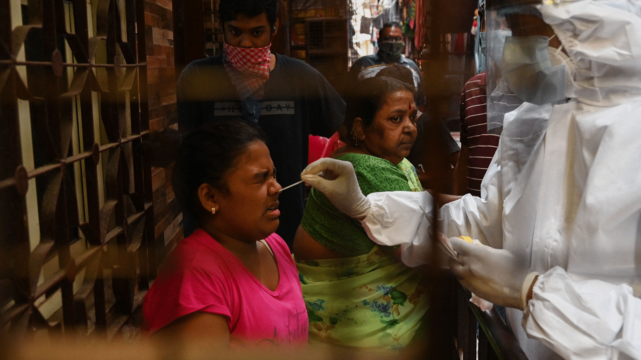 A health worker wearing protective gear takes a nasal swab sample of a resident for a Covid-19. Credit: AFP Photo