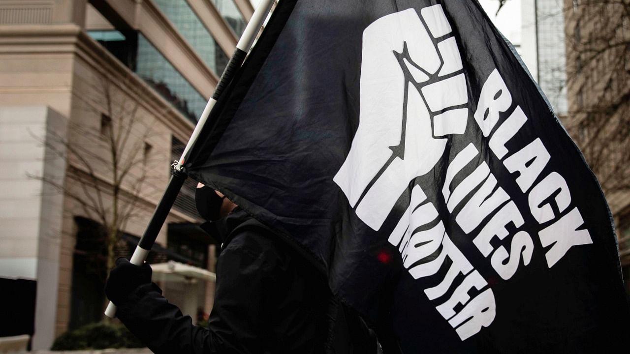 A protester carries a "Black Lives Matter" flag during a demonstration as jury selection begins in Minneapolis for the trial of Derek Chauvin, the former policeman accused of killing George Floyd, a Black man, in Portland, Oregon, US March 8, 2021. Credit: Reuters File Photo