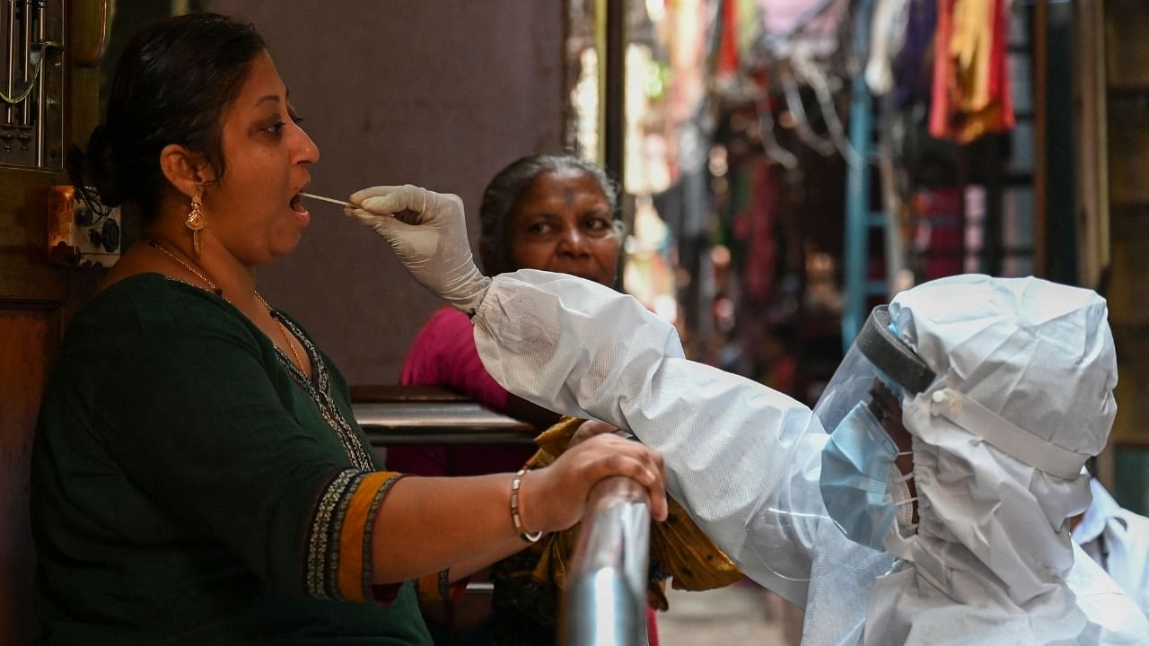 A health worker wearing protective gear takes a swab sample of a resident for a Covid-19 coronavirus test at Dharavi slum in Mumbai on March 11, 2021. Credit: AFP Photo