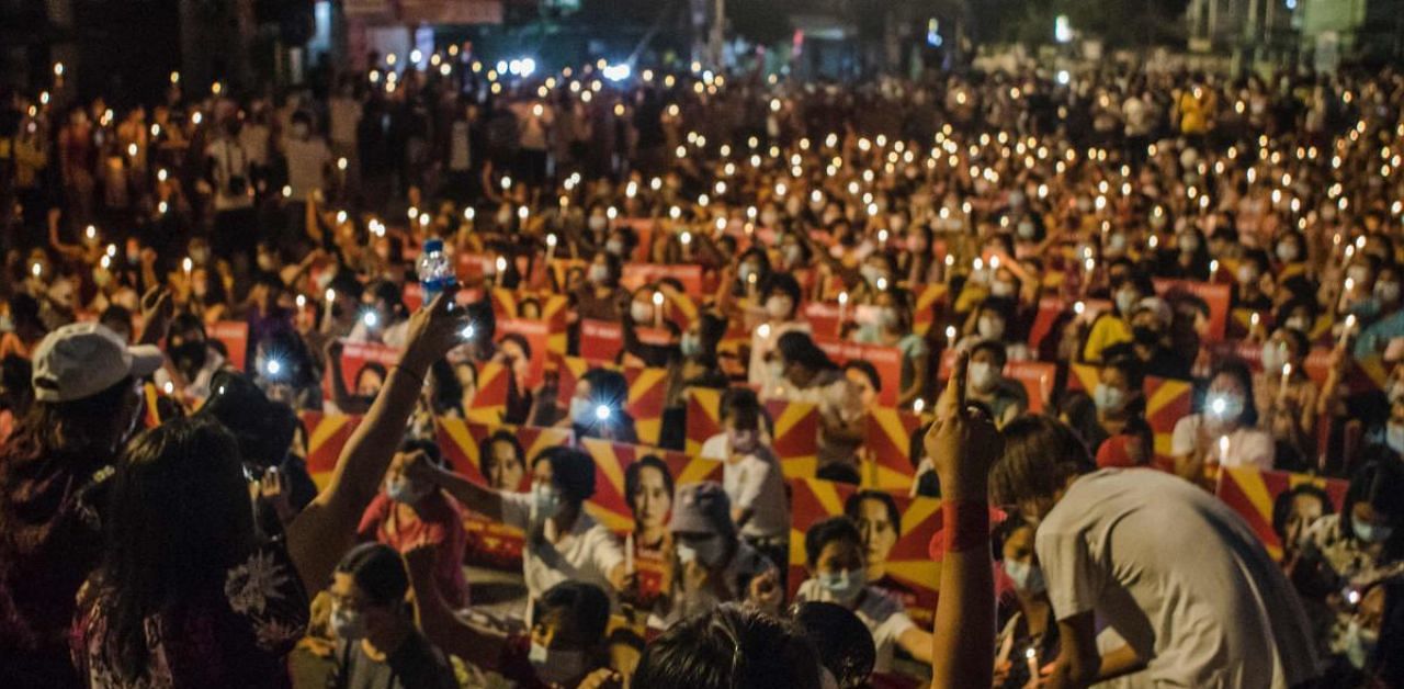 Protesters with placards with the image of detained Myanmar civilian leader Aung San Suu Kyi hold a candlelight vigil and shout slogans during a demonstration against the military coup in Yangon. Credit: AFP photo. 