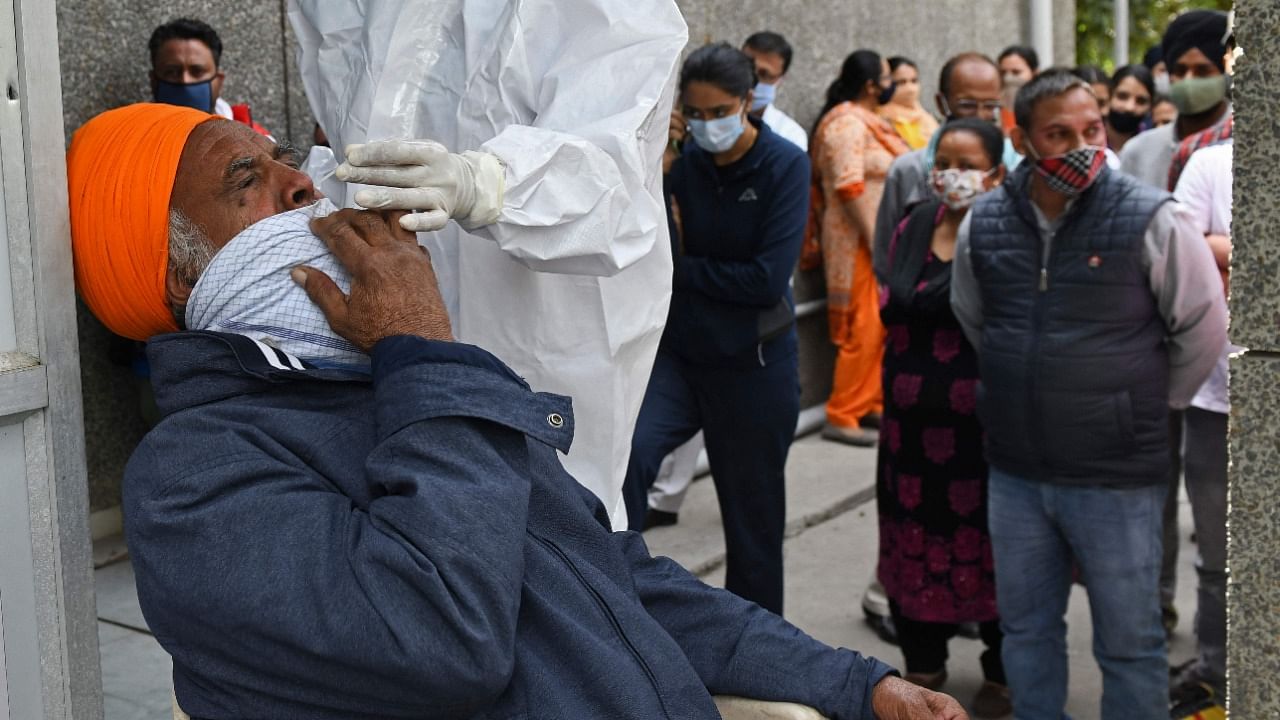 A health worker collects a nasal swab sample from a man to test for the Covid-19 coronavirus at a hospital in Amritsar on March 13, 2021. Credit: AFP Photo