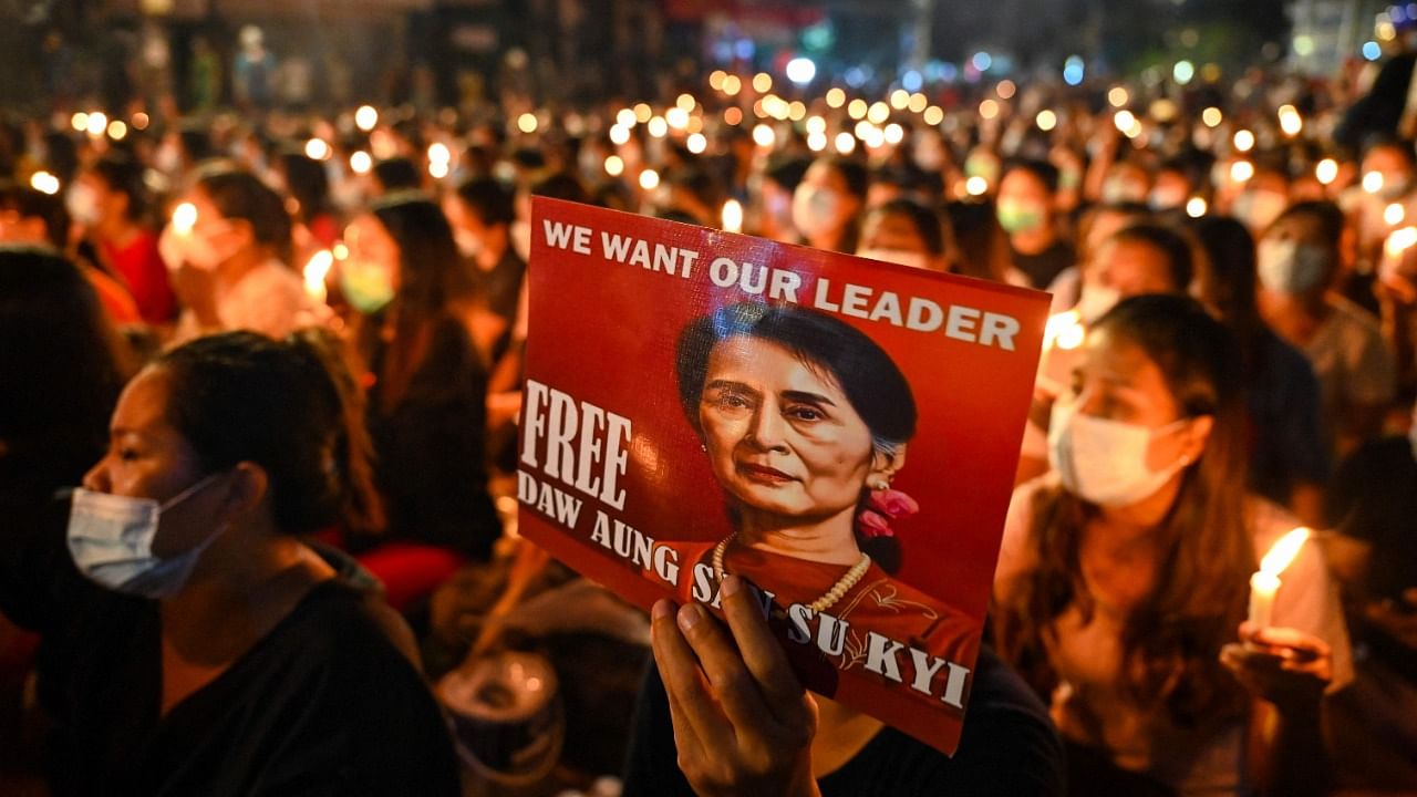 A protester holds a poster with an image of detained civilian leader Aung San Suu Kyi during a candlelight vigil to honour those who have died during demonstrations against the military coup in Yangon on March 13, 2021. Credit: AFP Photo