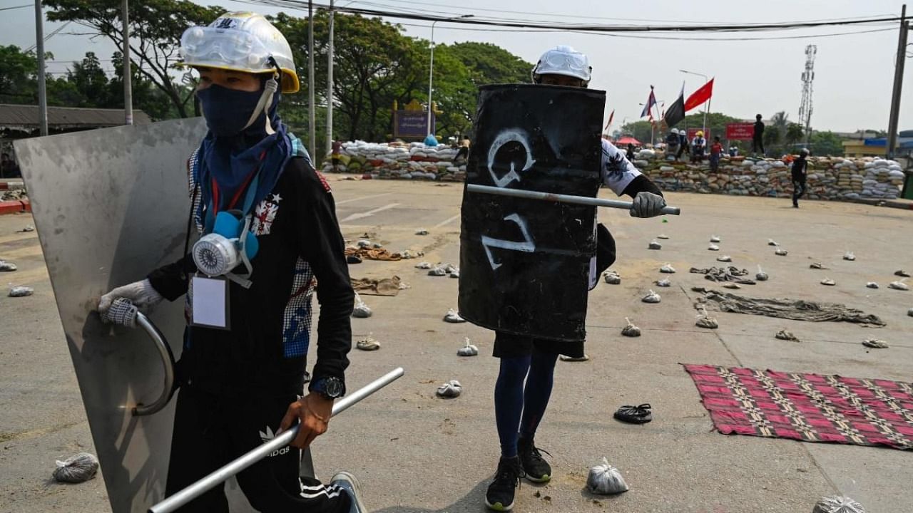 Protesters hold homemade shields as they walk through an area with makeshift barricades to deter security forces during demonstrations against the military coup in Yangon. Credit: AFP.