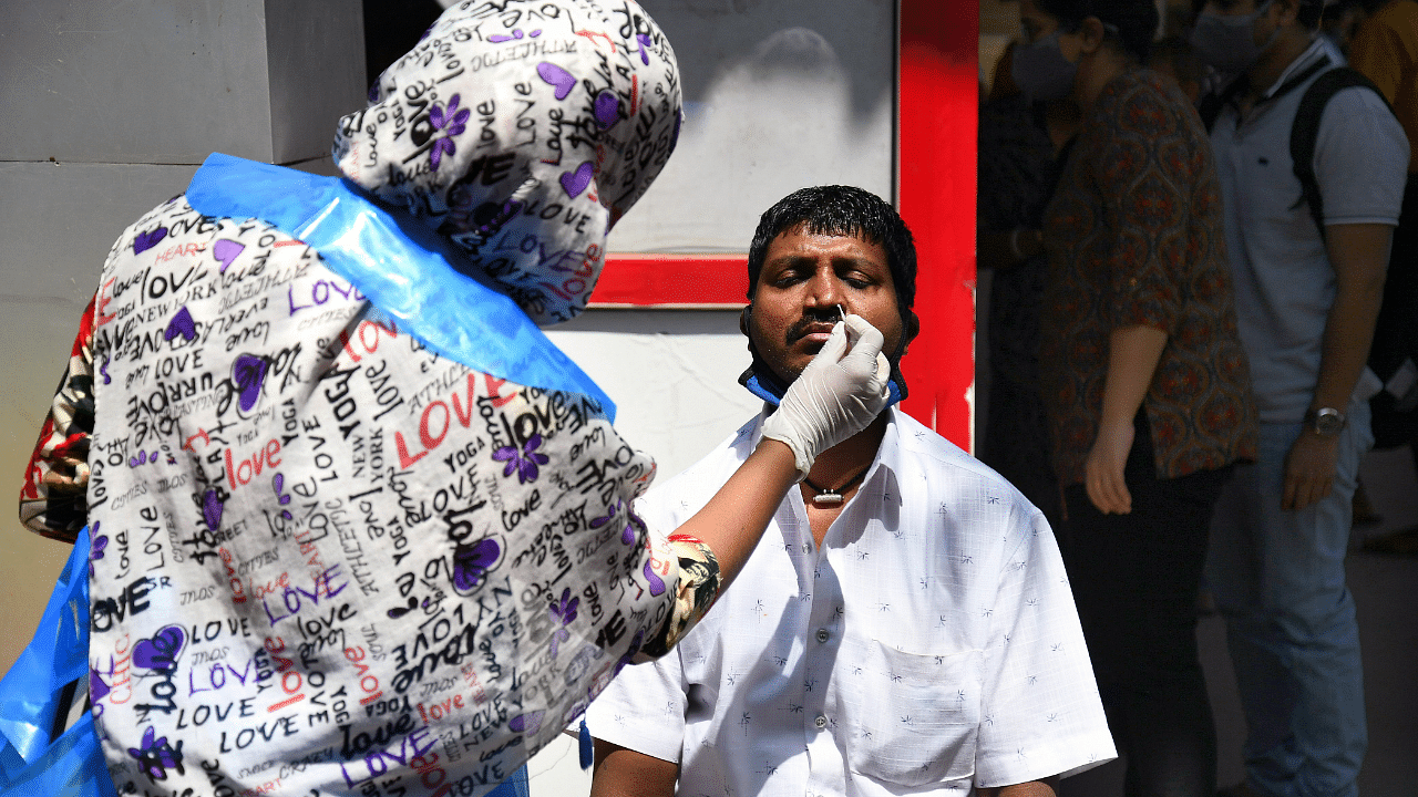 A health worker takes a swab of a passenger for a Covid-19 test in Bengaluru. Credit: DH Photo